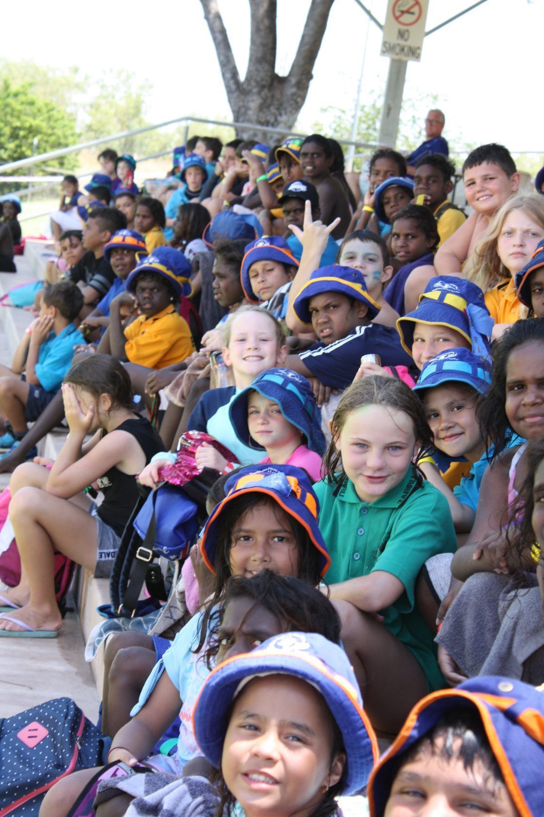 A group of children wearing hats are sitting in a stadium.