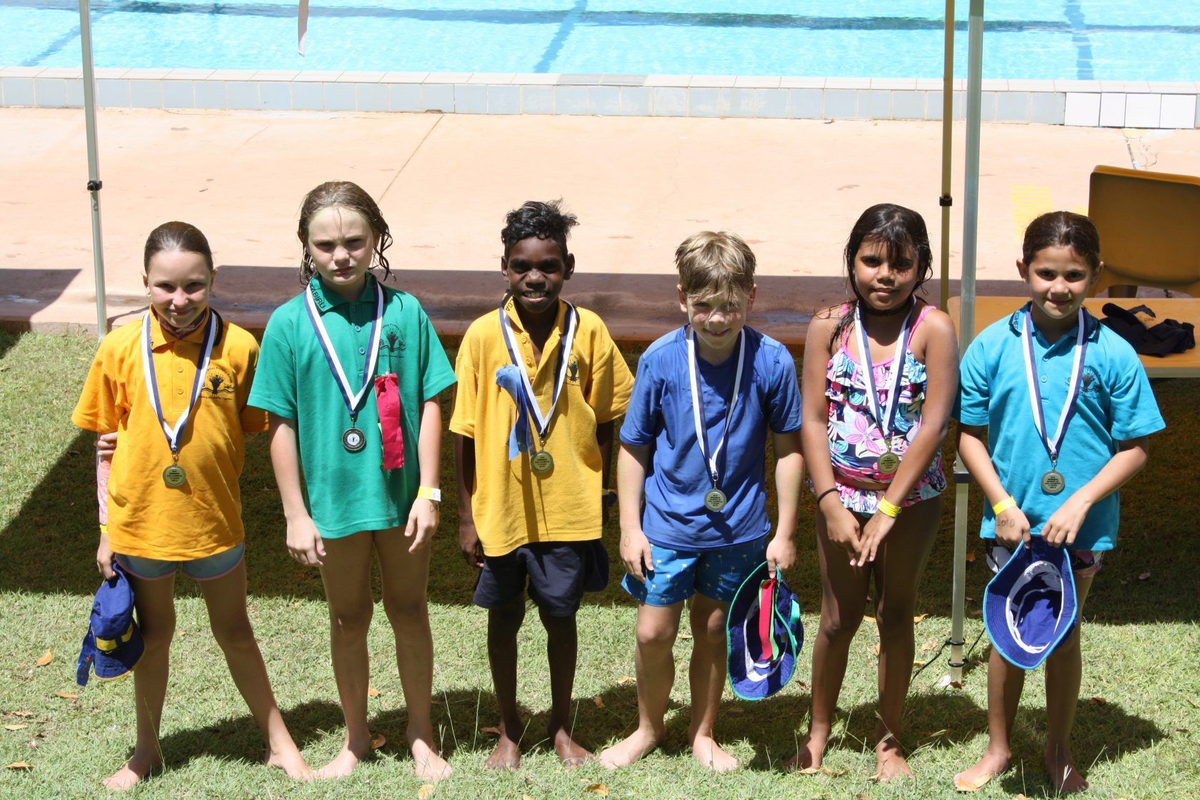 A group of children standing next to each other with medals around their necks
