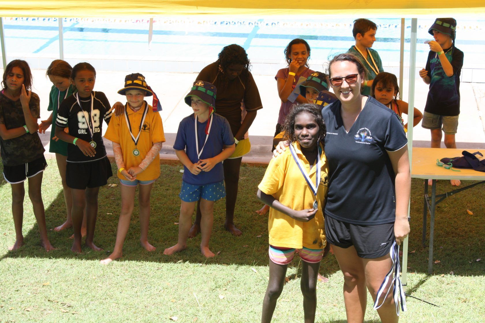 A group of children standing in front of a swimming pool
