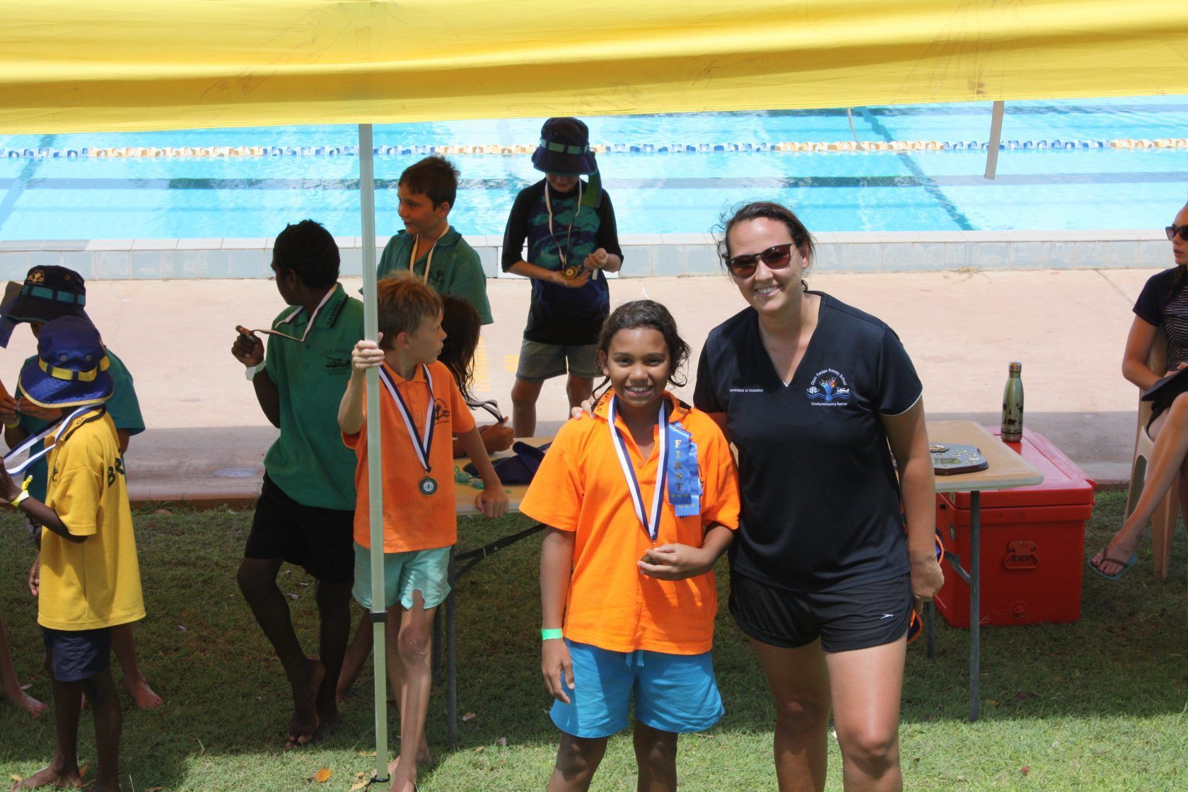 A woman and a boy are posing for a picture in front of a swimming pool.