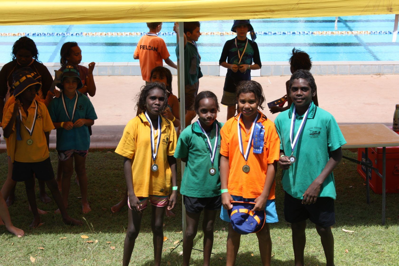 A group of children are posing for a picture in front of a pool