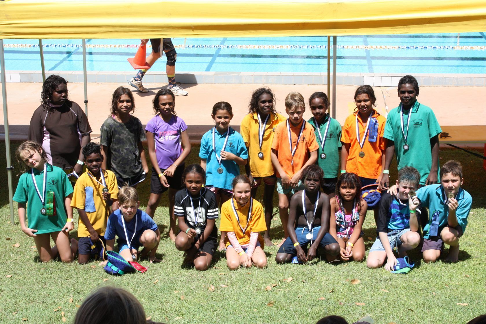 A group of children are posing for a picture in front of a pool.