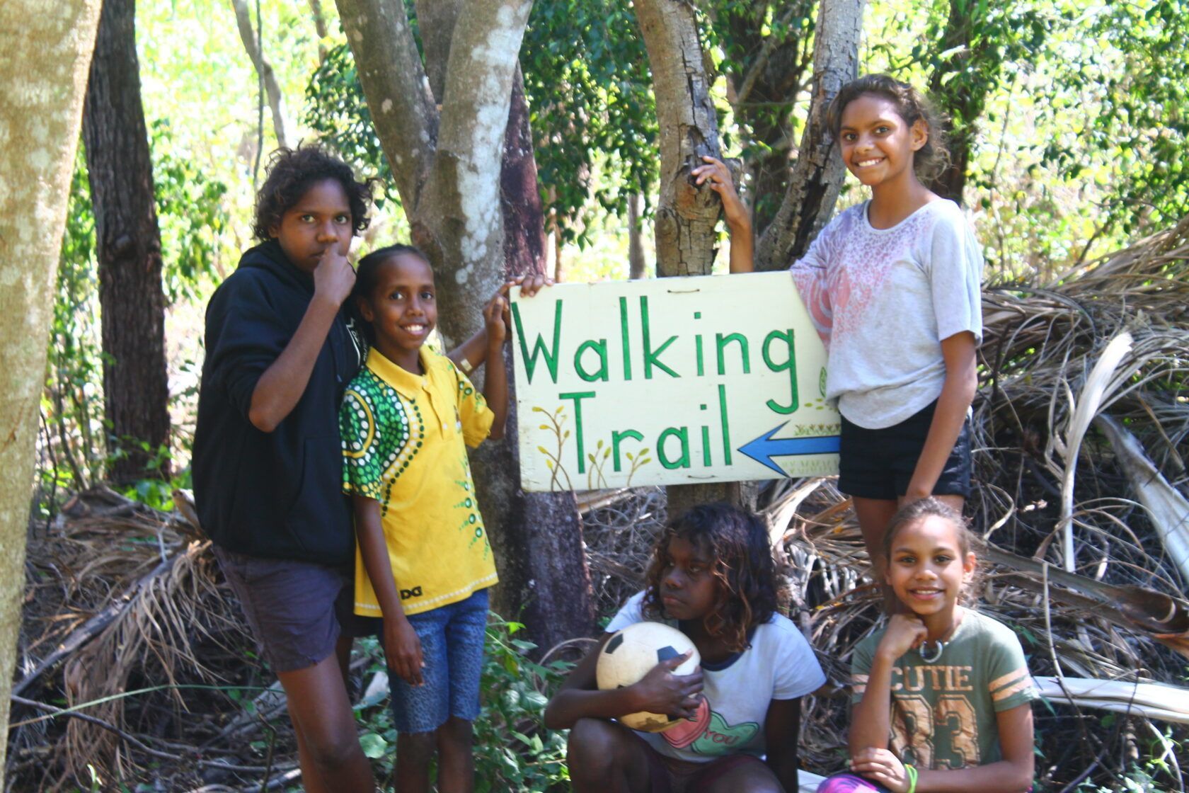 A group of children holding a sign that says walking trail