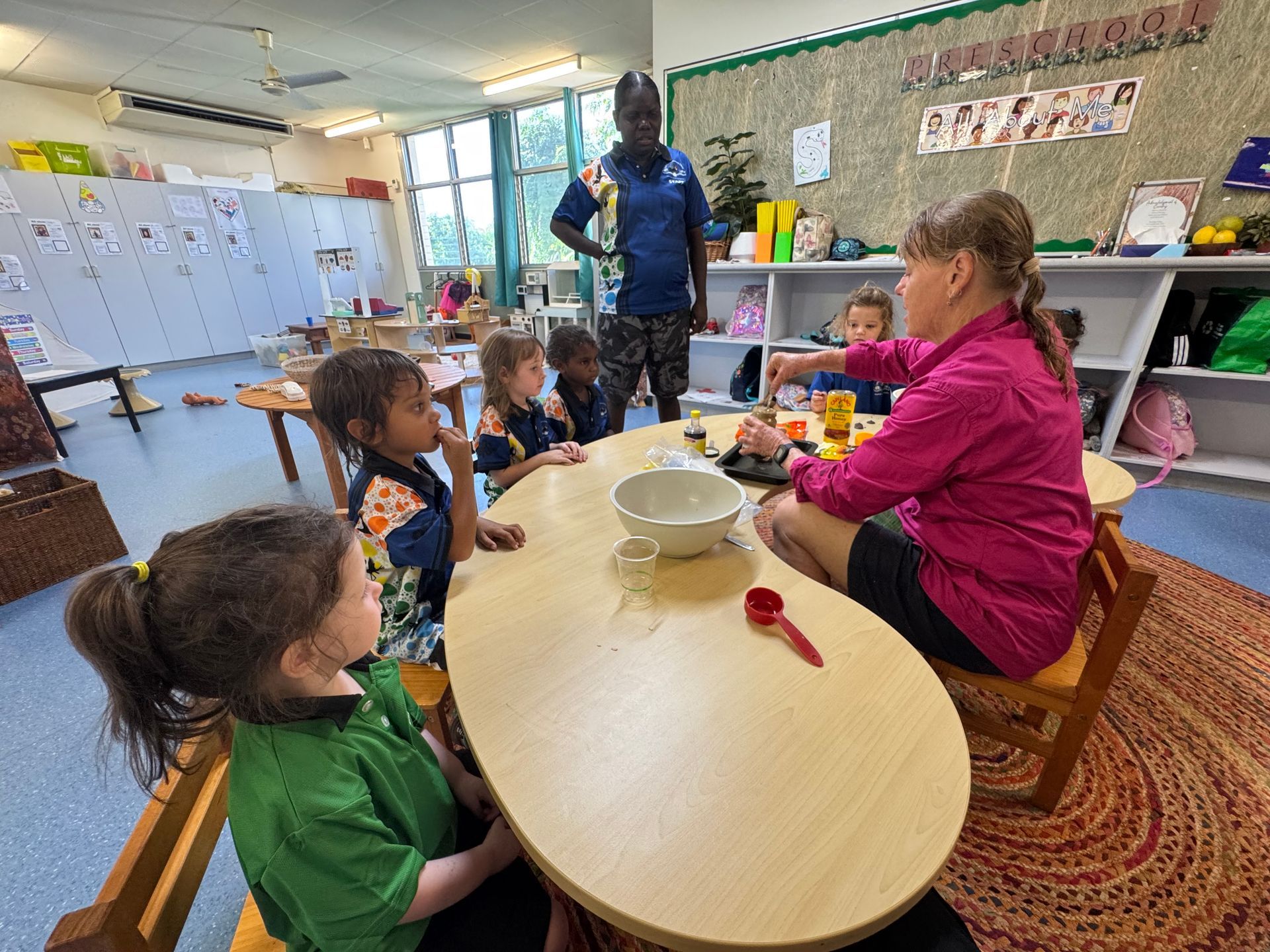A group of children are sitting at a table in a classroom.