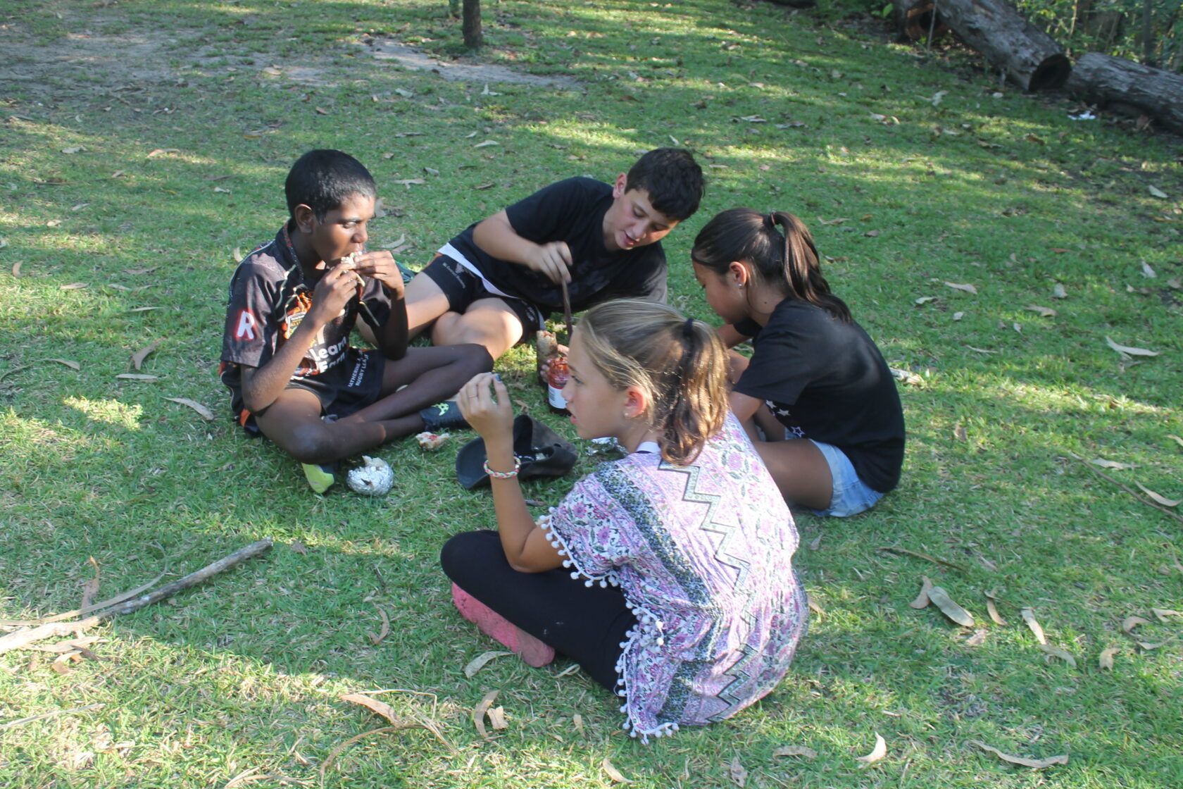 A group of children are sitting in a circle on the grass.