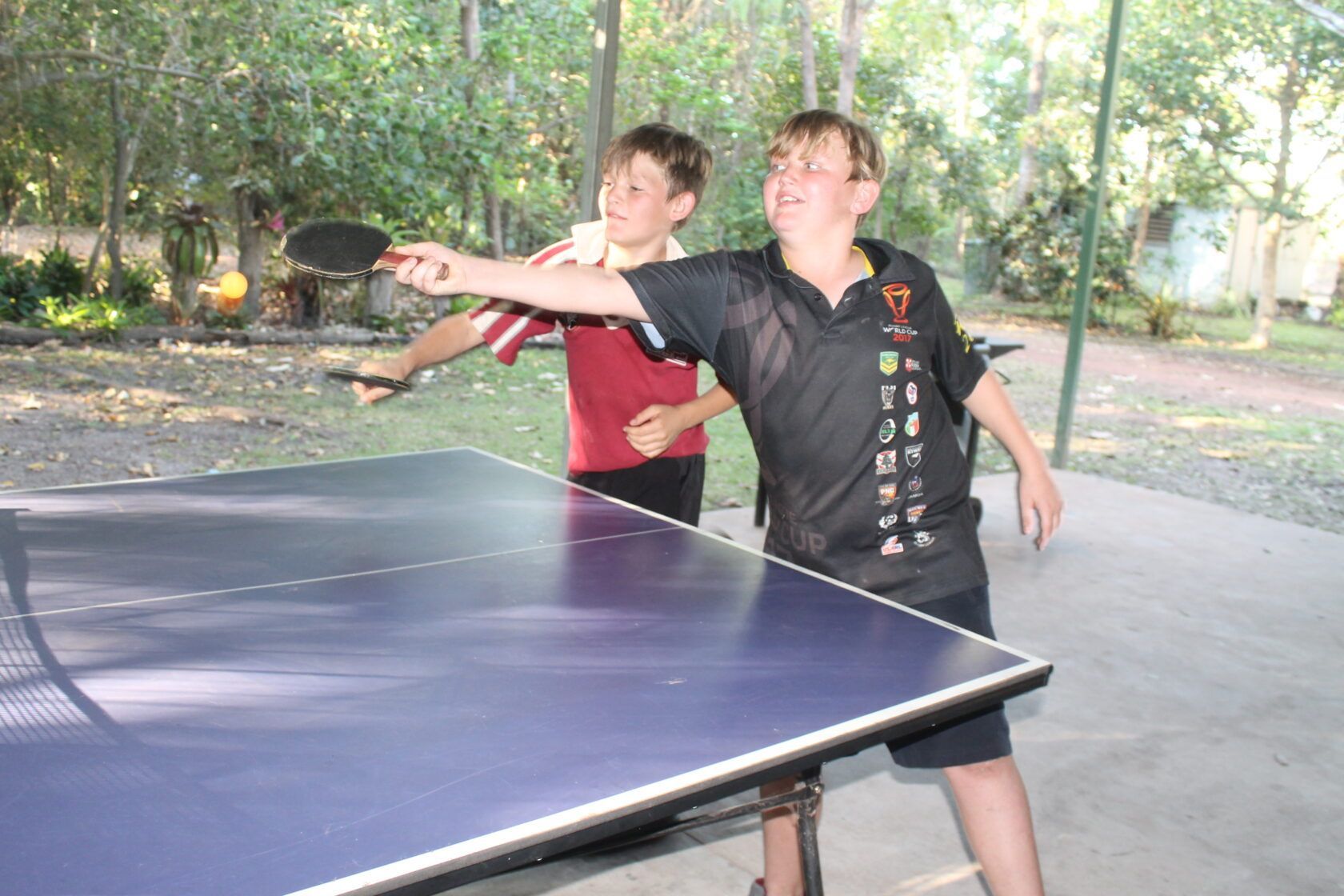 Two young boys are playing ping pong on a table