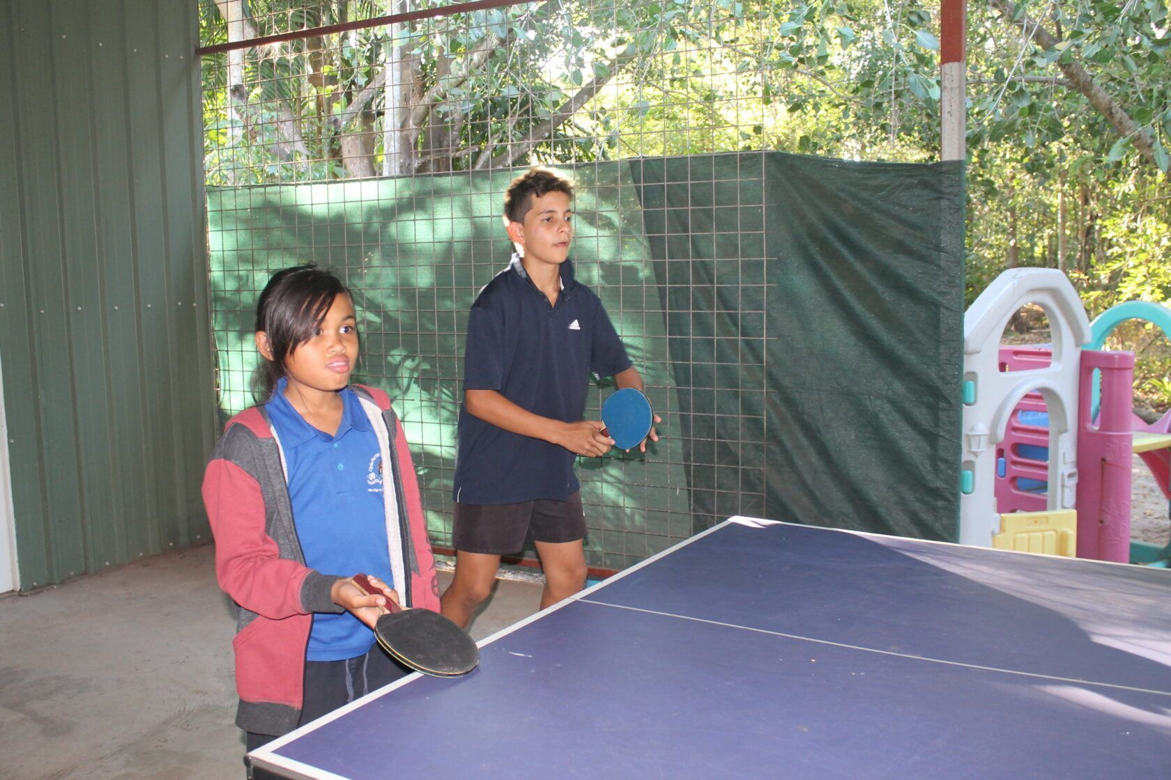 A boy and a girl are playing ping pong on a table