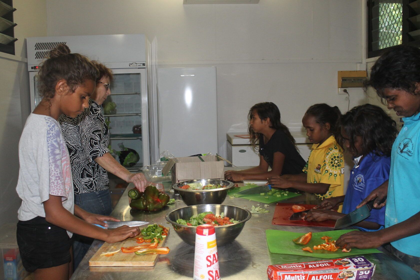 A group of children are preparing food in a kitchen.
