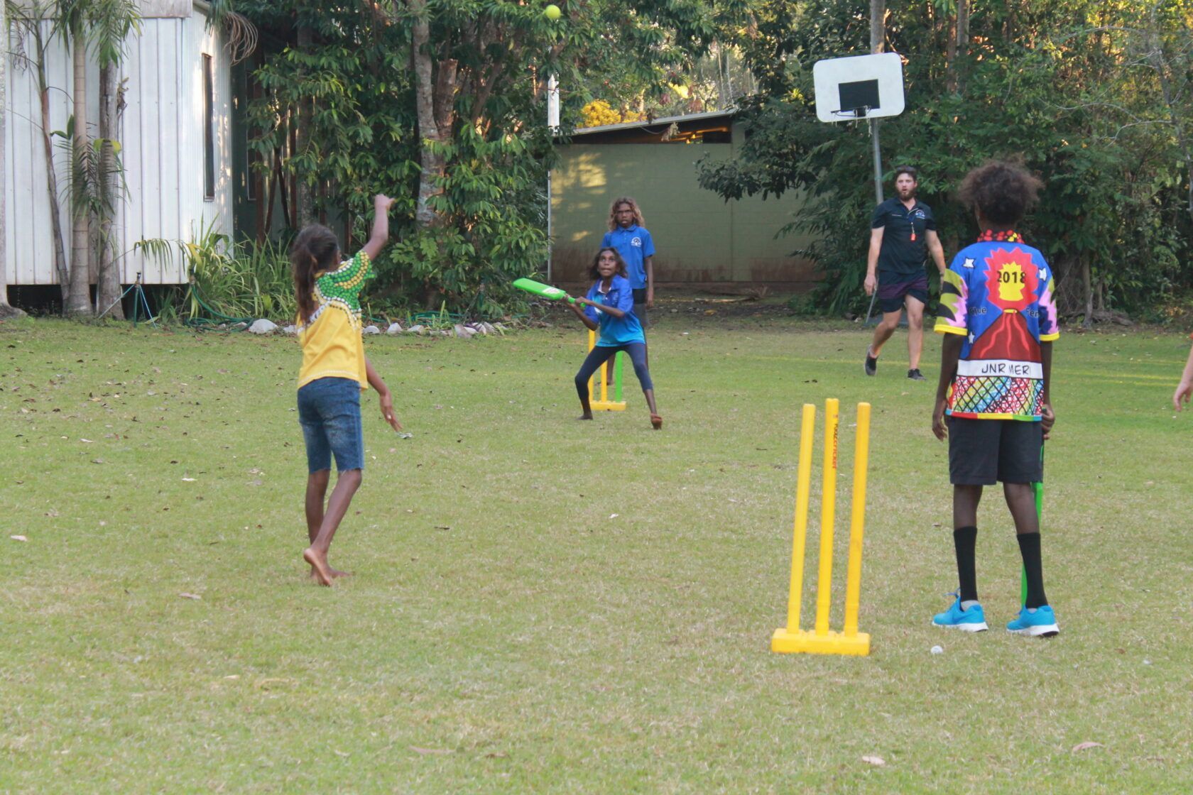 A group of children are playing cricket on a lush green field.