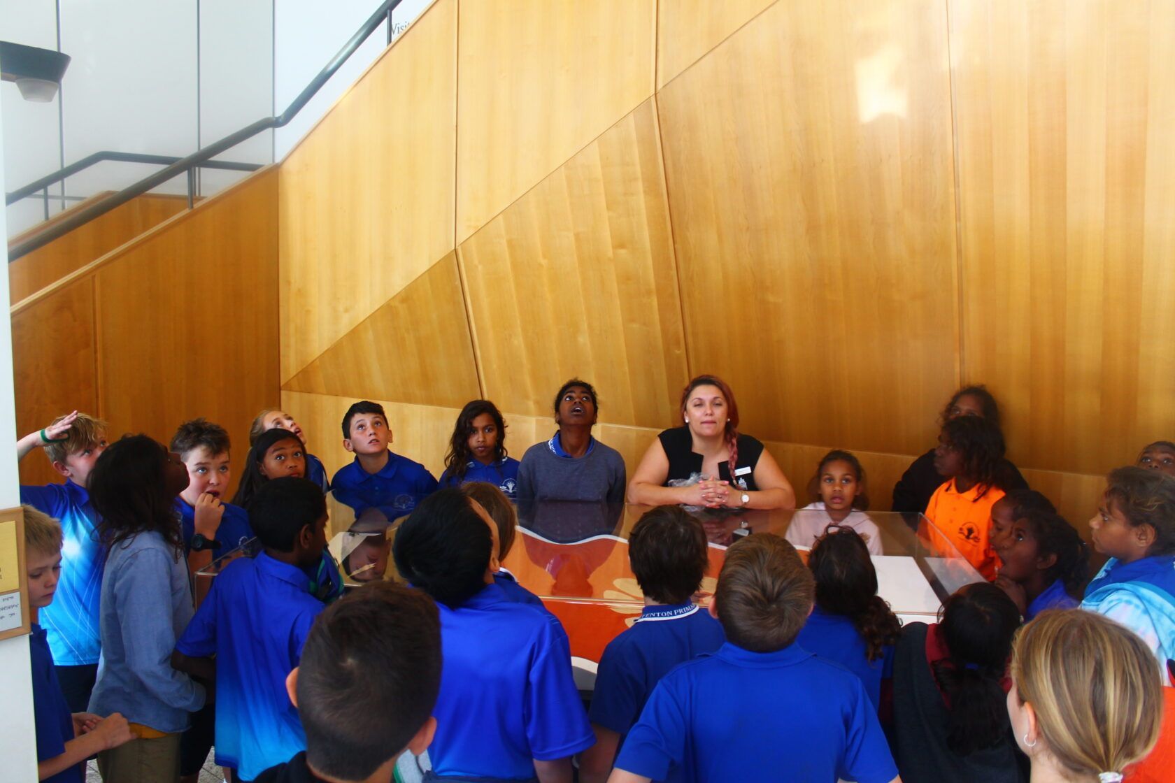 A group of people in blue shirts are gathered around a table