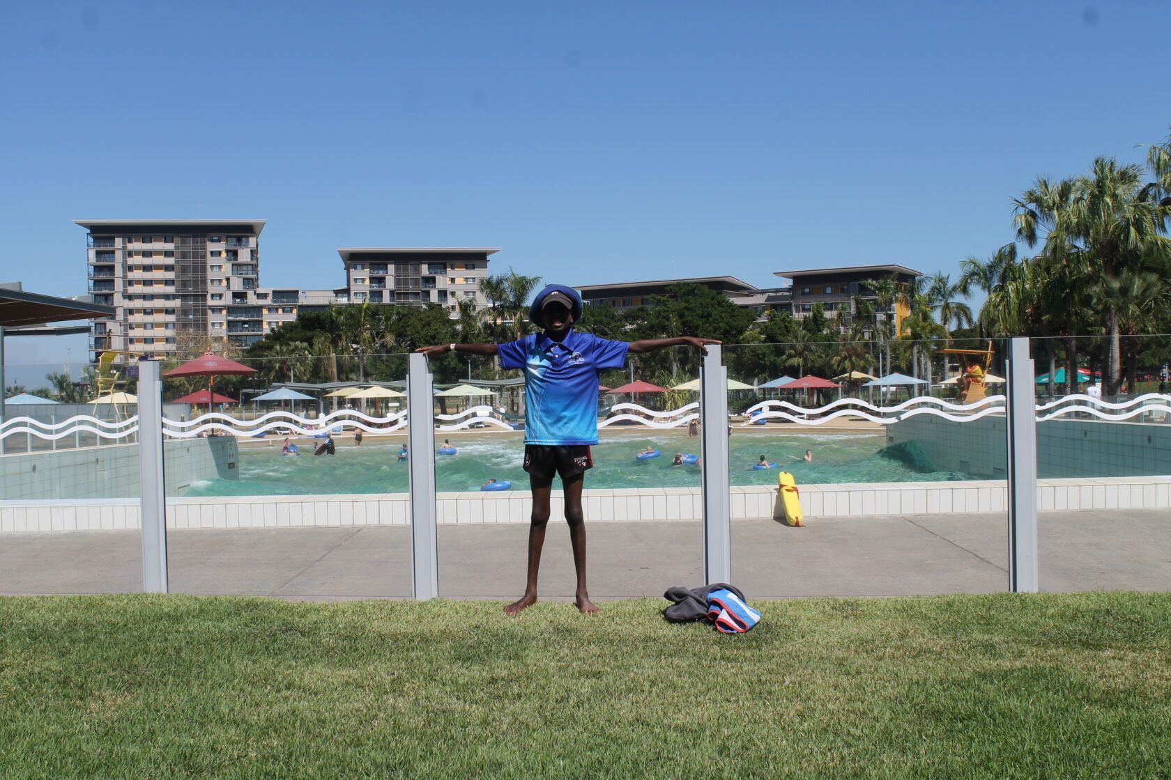 A person is standing in front of a fence in front of a swimming pool.