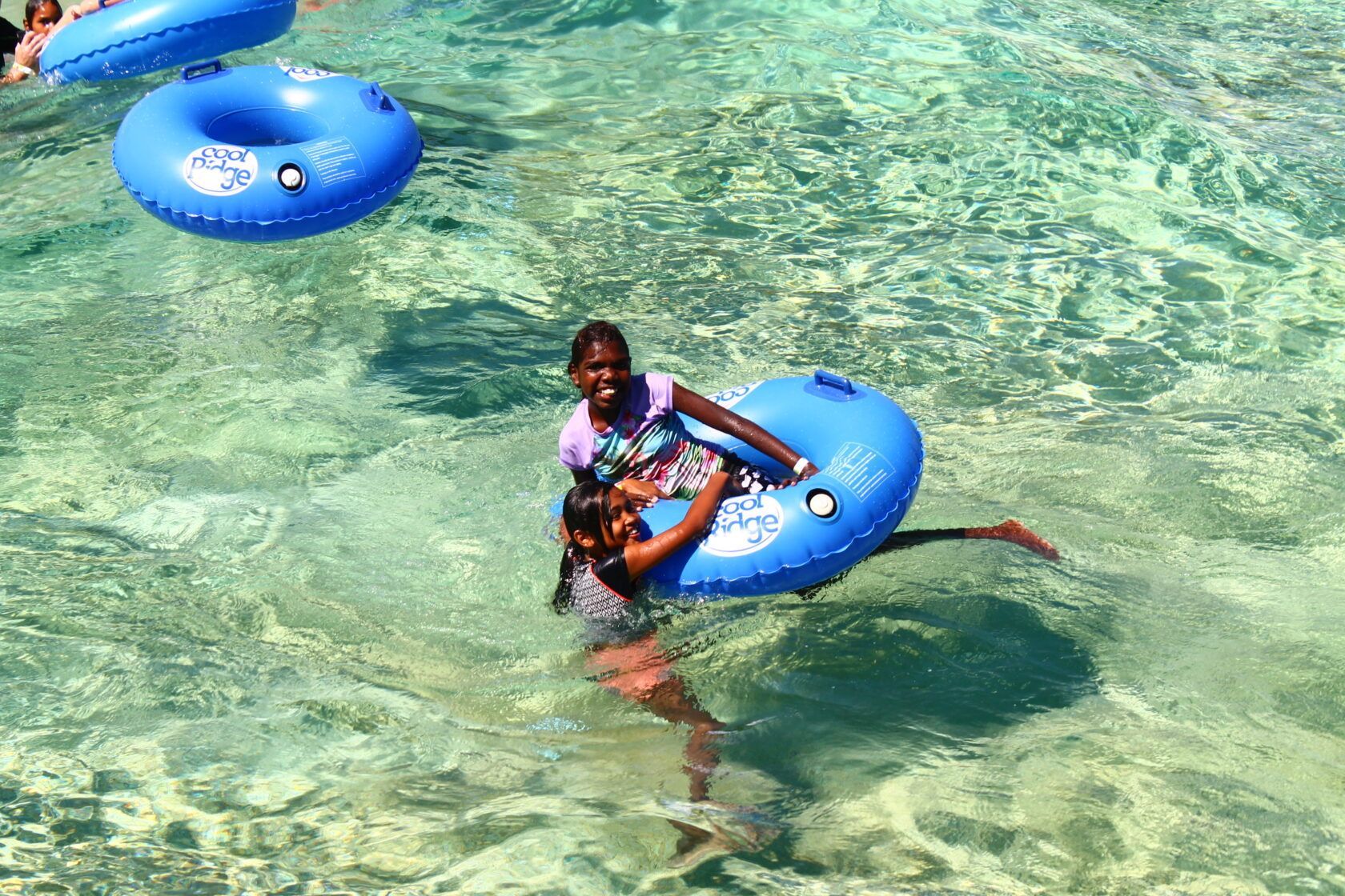 A group of people are floating on blue inner tubes in the water.