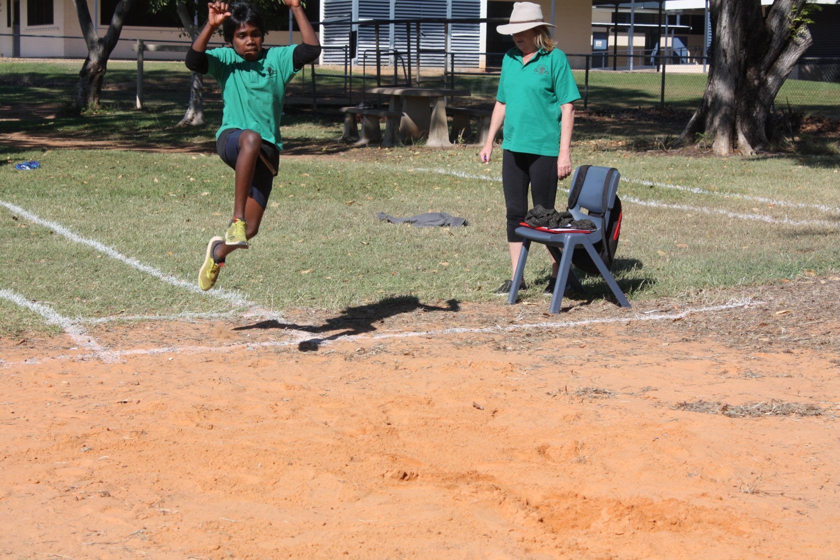 A young boy is jumping in the air while a woman watches.