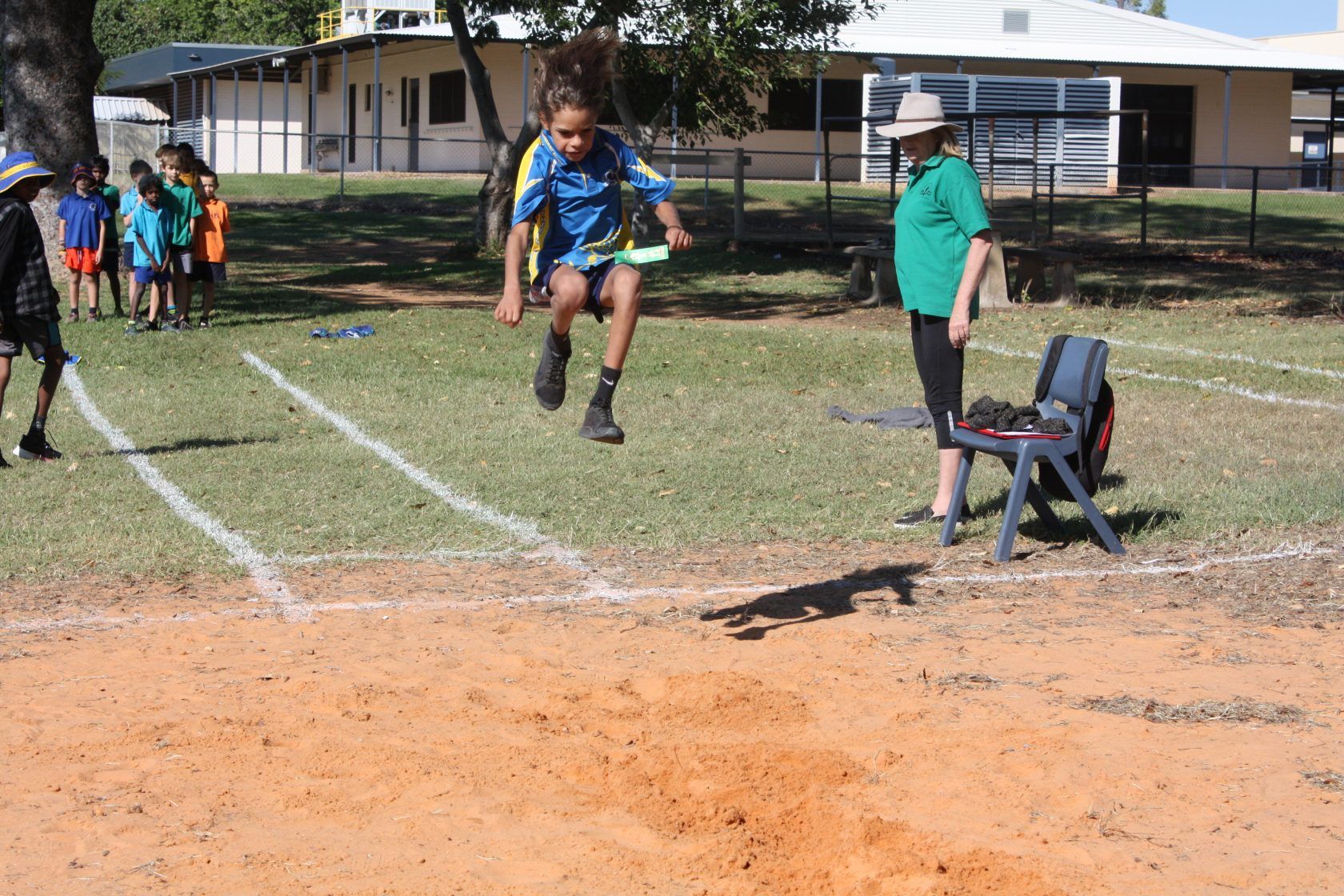 A young boy is jumping in the air while a woman watches.