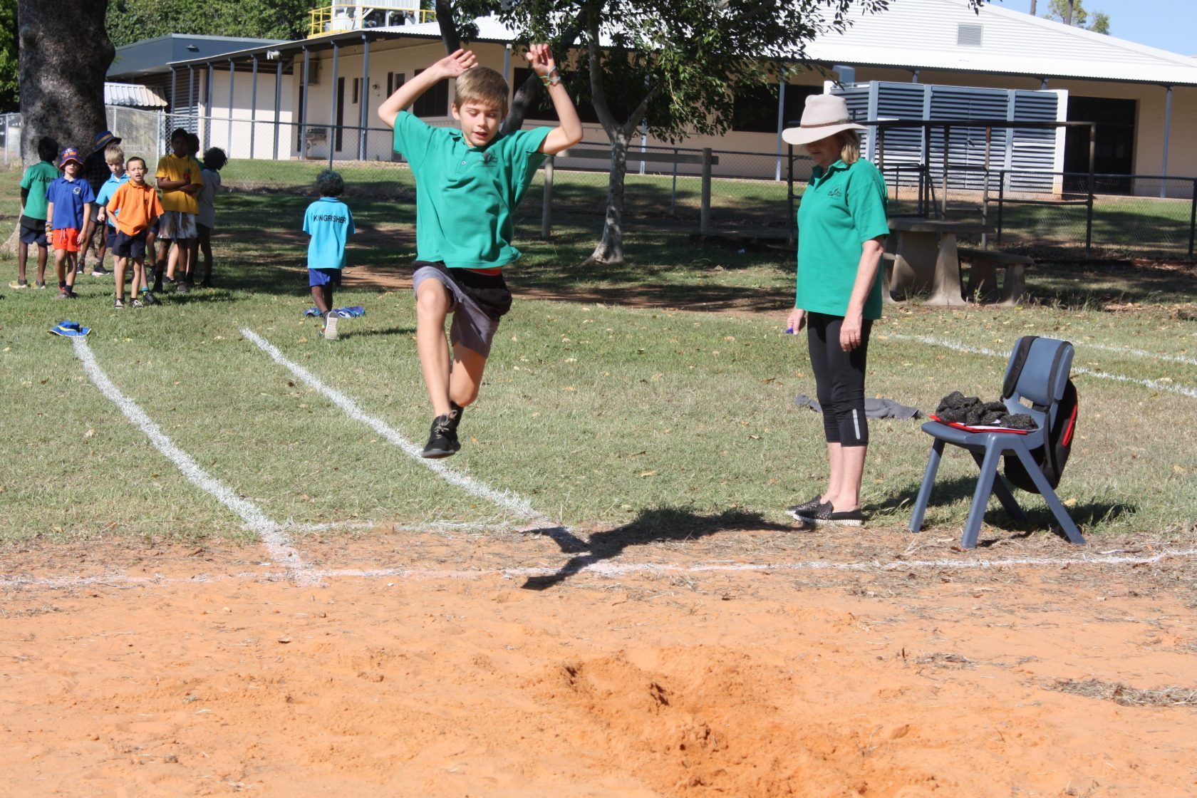 A boy in a green shirt is jumping in the air