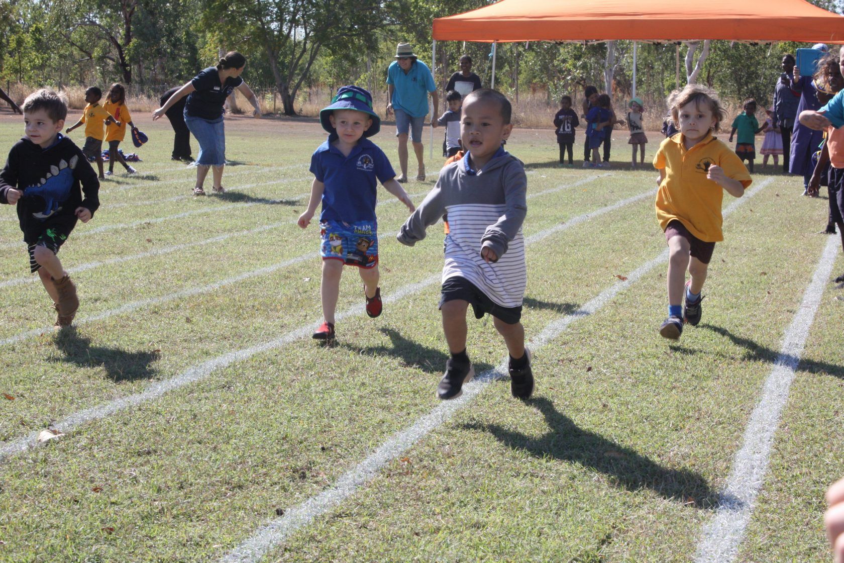 A group of young children are running on a track.
