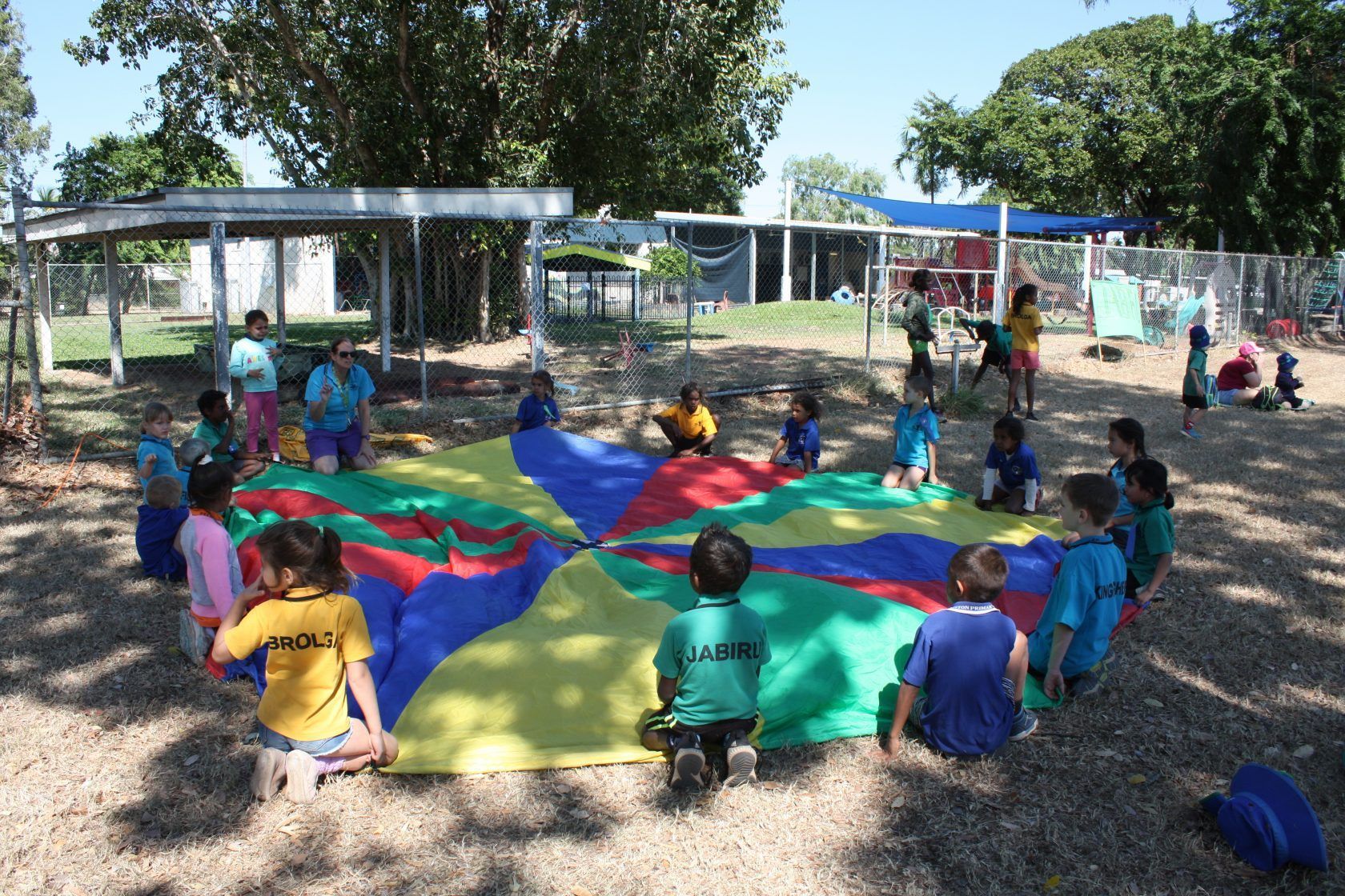 A group of children are playing with a parachute in a park