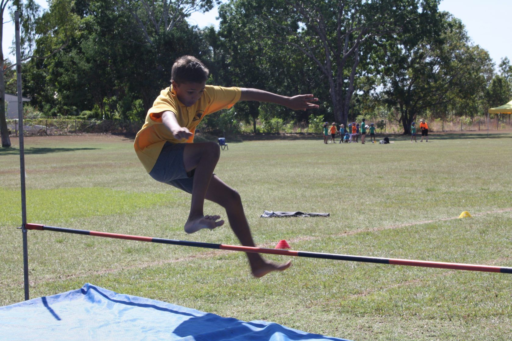 A young boy is jumping over a pole in a field