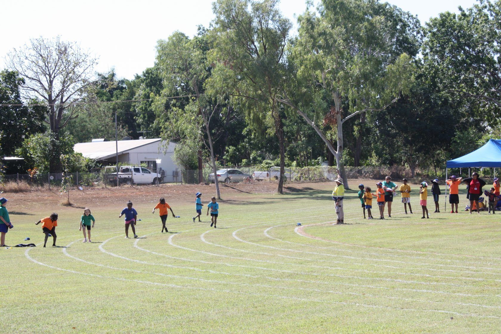 A group of children are running on a track in a field.