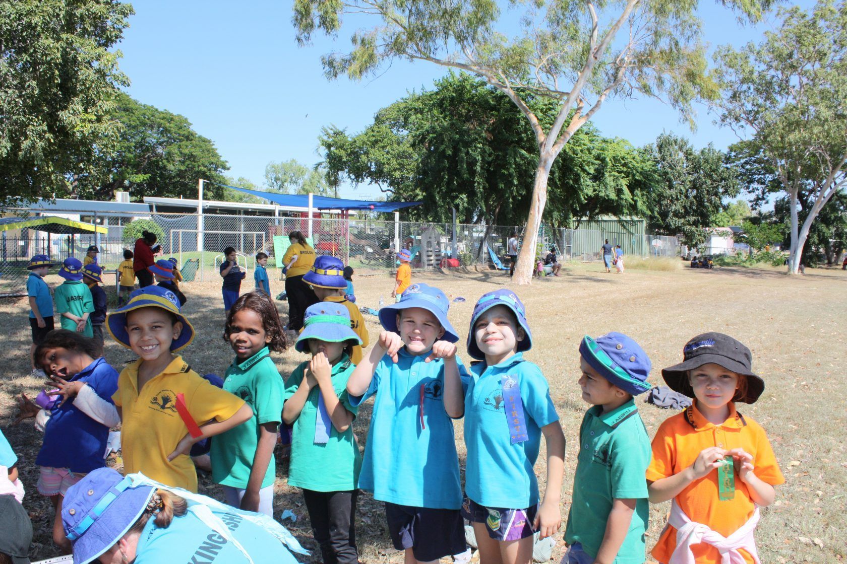 A group of children wearing hats and shirts are standing in a field
