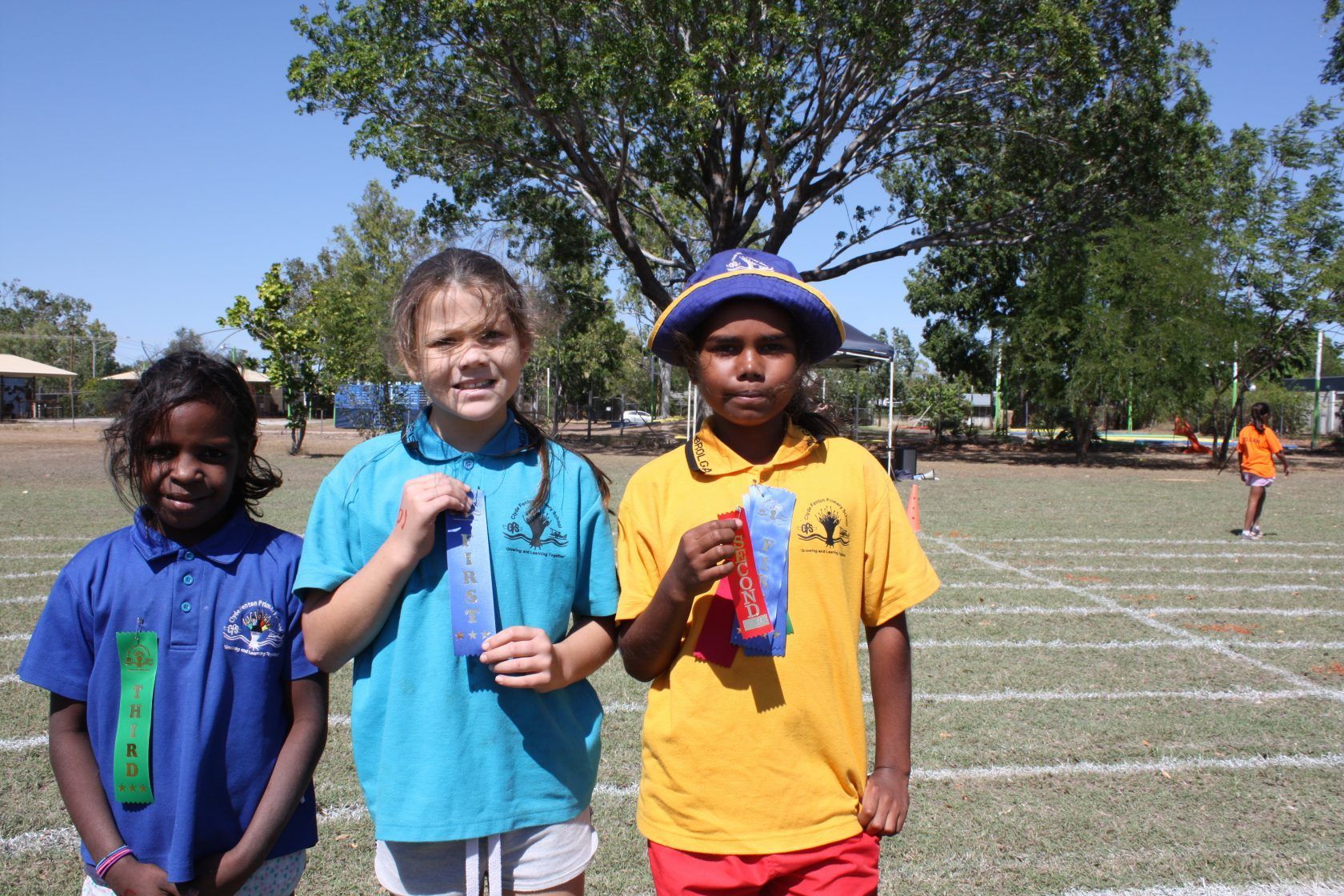 Three children are posing for a picture in a field.