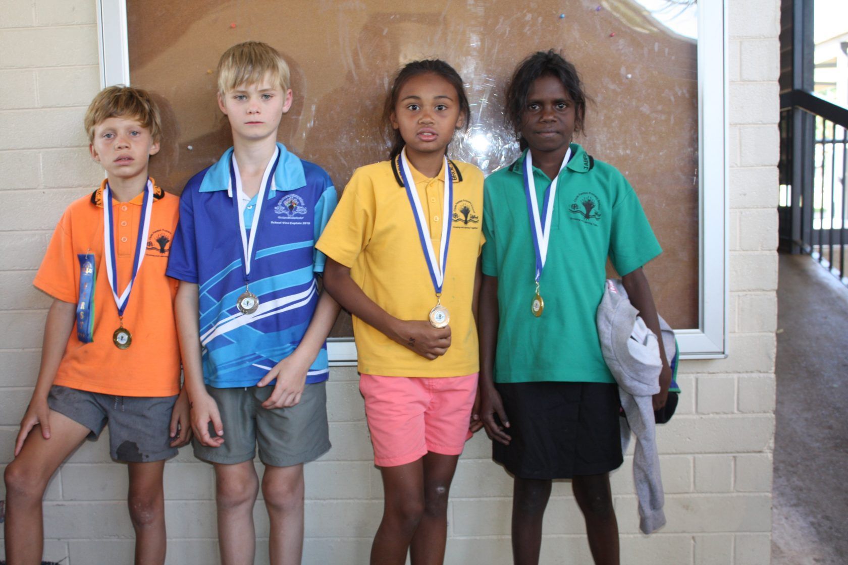 A group of children standing next to each other with medals around their necks