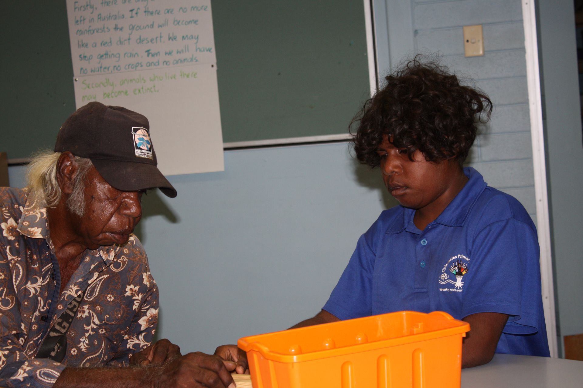 A man and a woman are sitting at a table with an orange container
