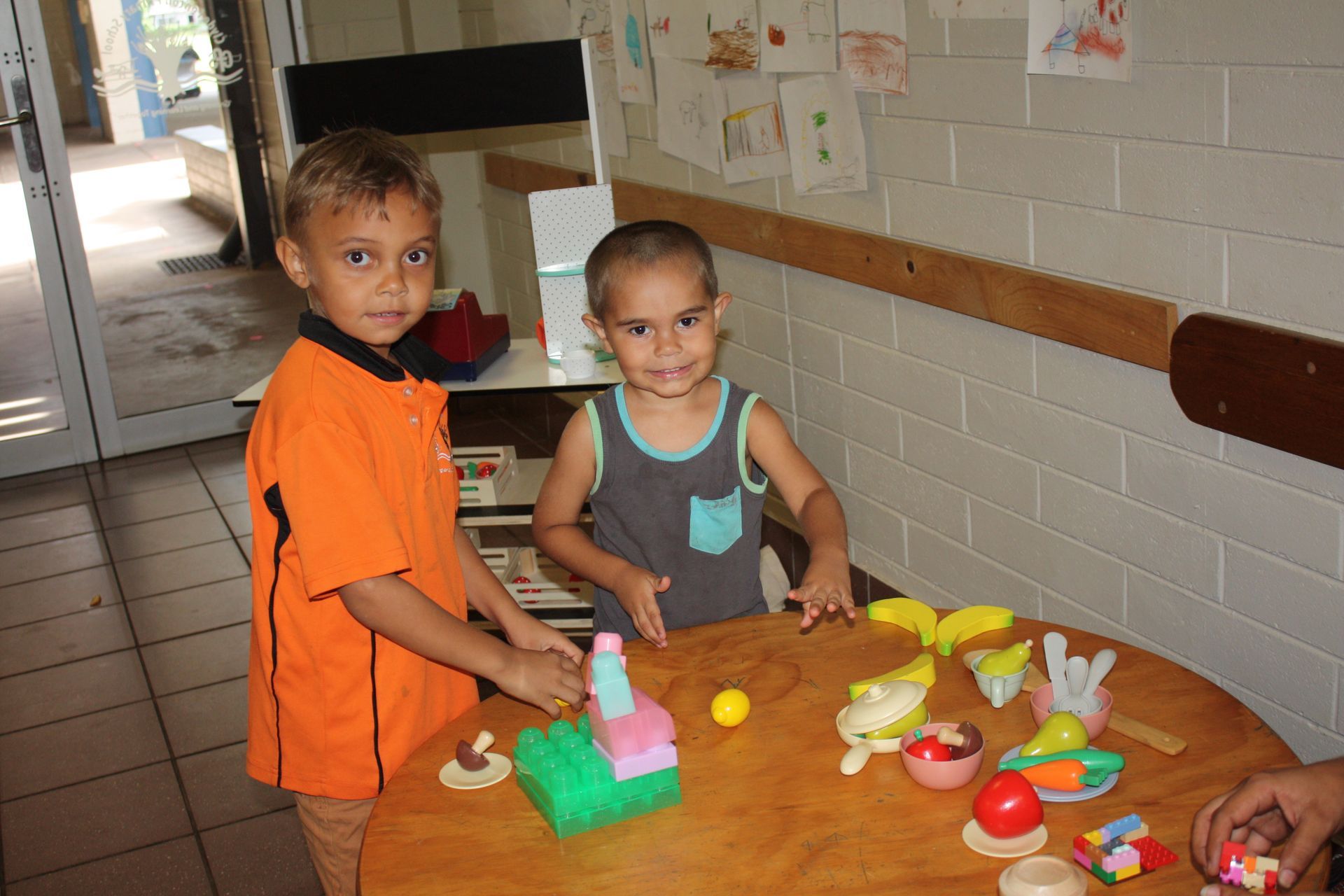 Two young boys are playing with toys at a table