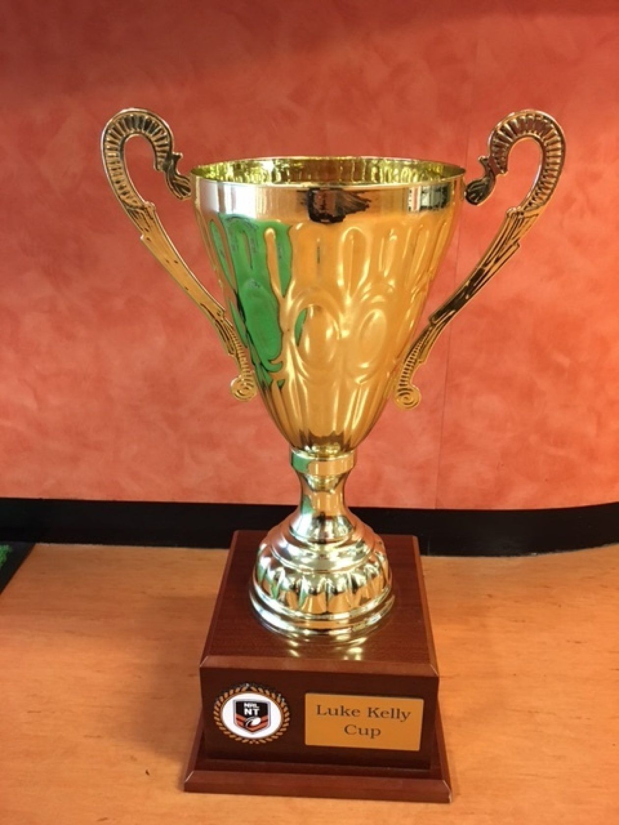 A gold trophy is sitting on a wooden table.