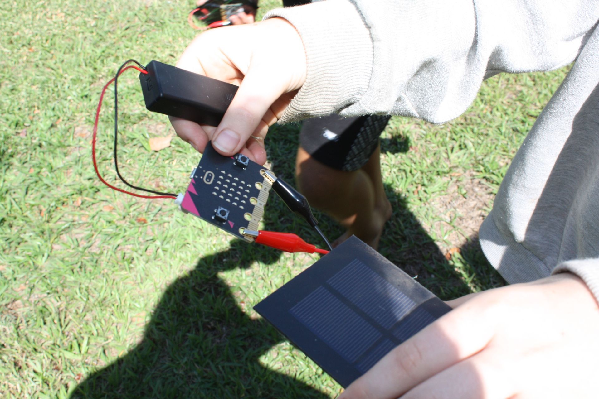 A person is holding a small electronic device with a battery attached to it
