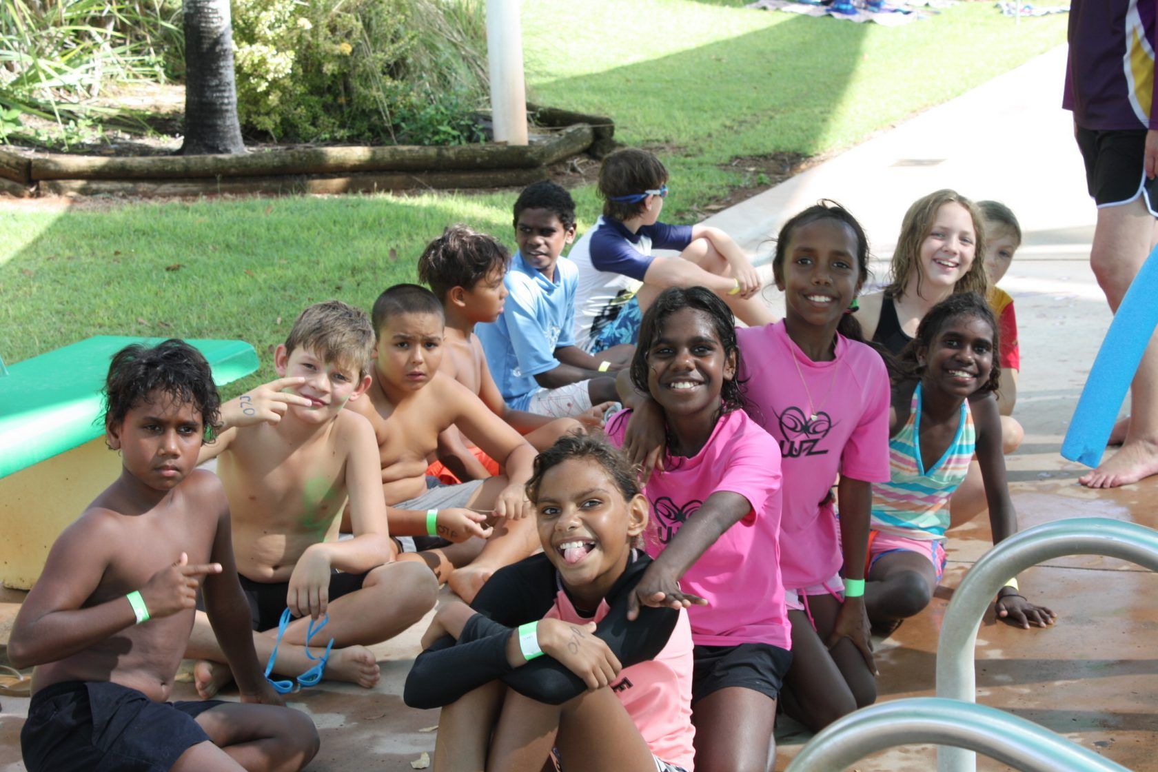 A group of children are posing for a picture in front of a pool.
