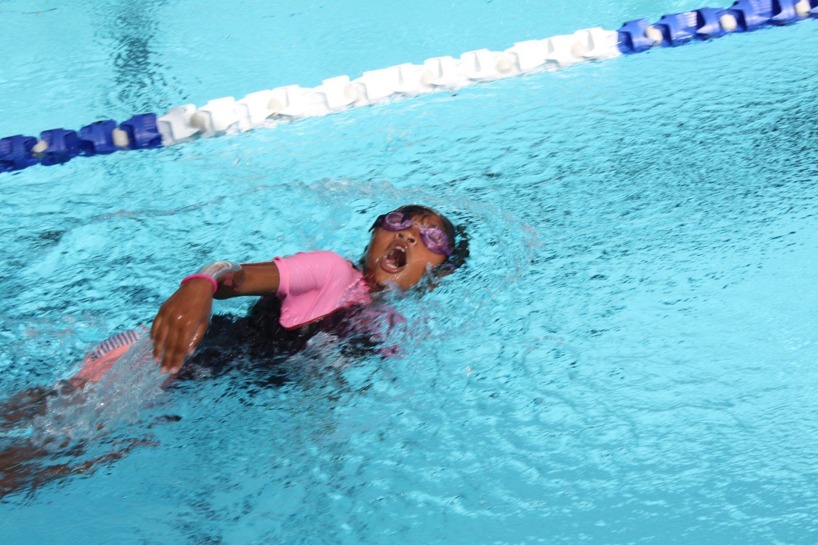 A young girl is swimming in a swimming pool.