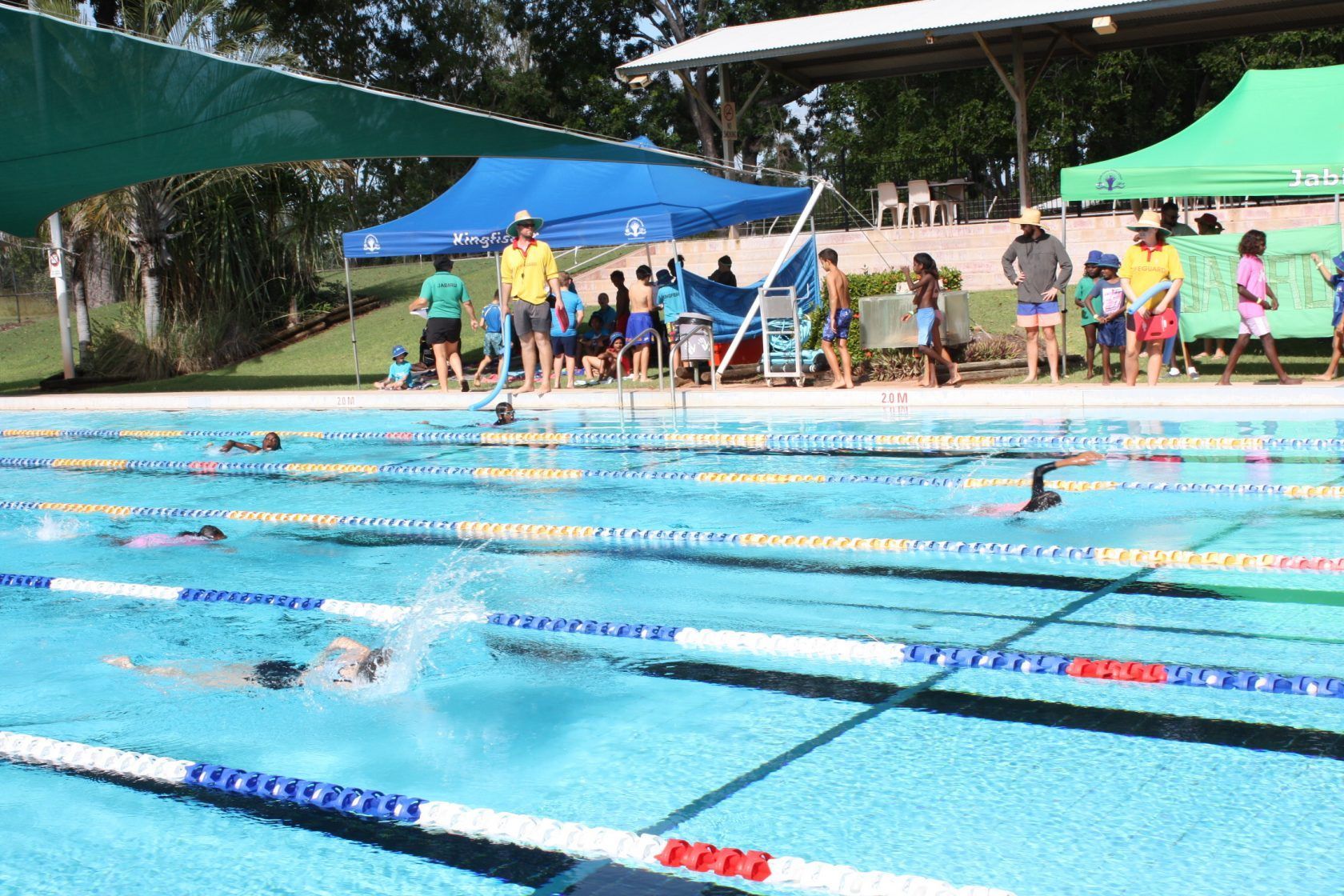 A group of people are standing around a swimming pool.