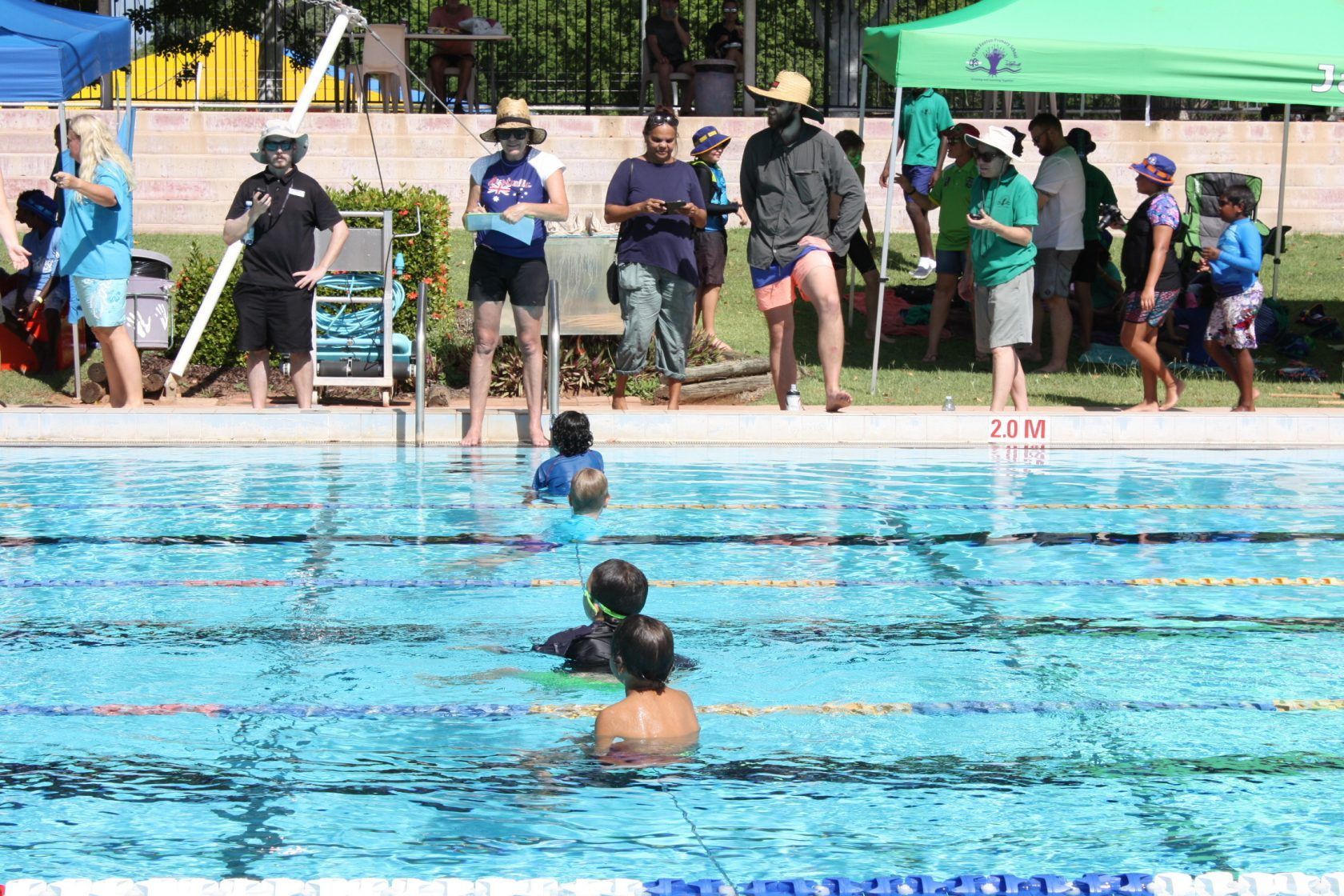 A group of people are standing around a swimming pool.