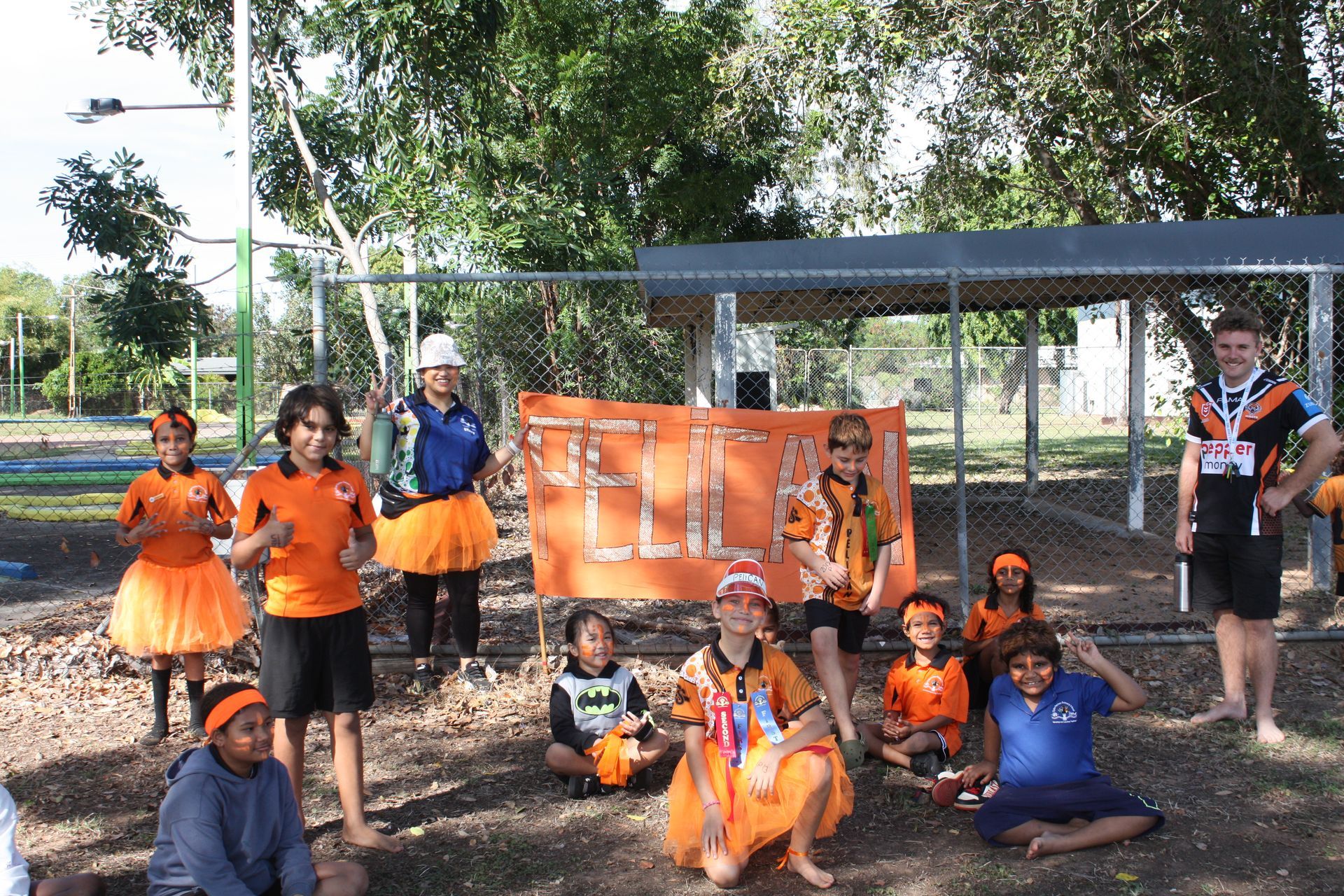 A group of people holding an orange sign that says feliz