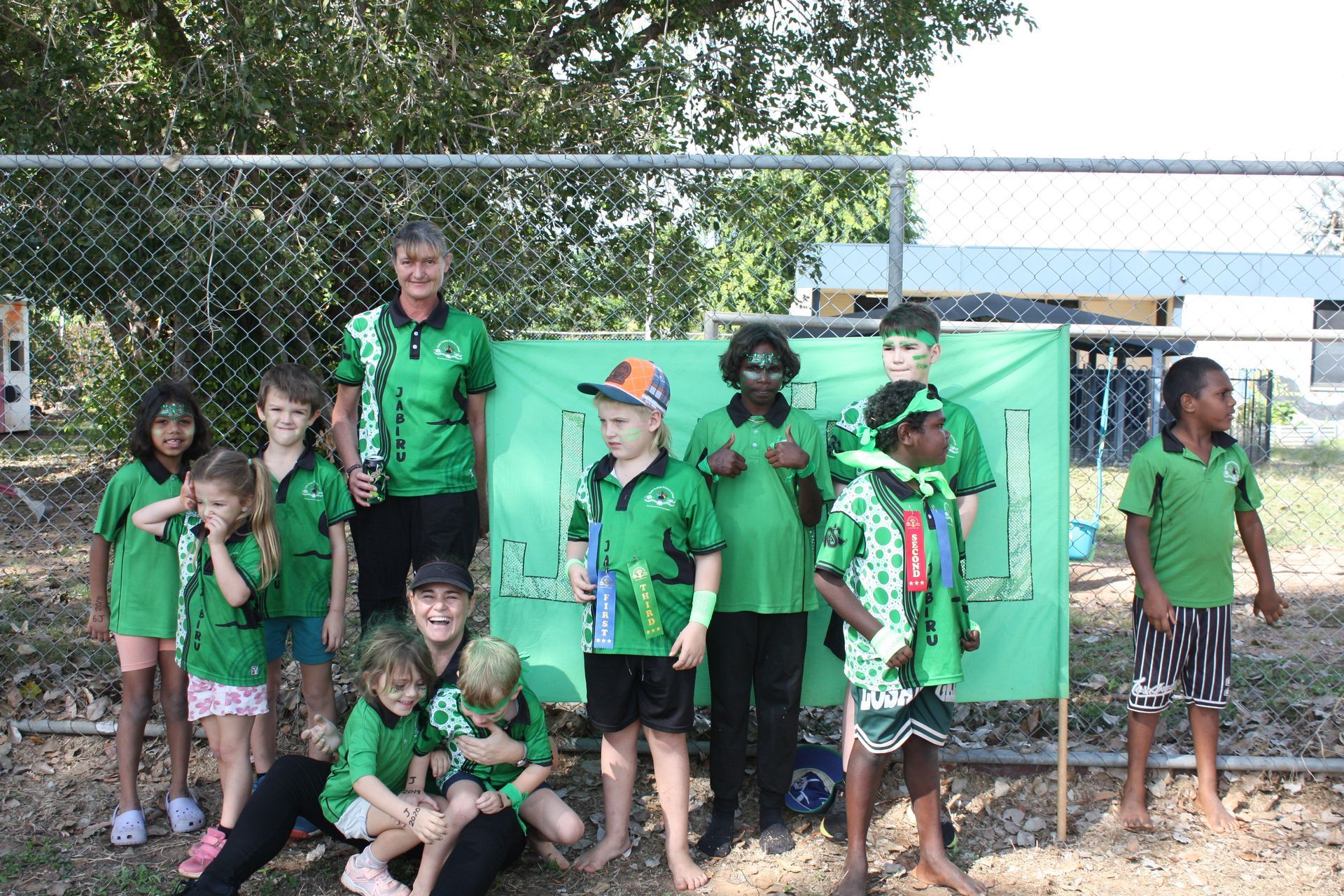 A group of children in green shirts are posing for a picture.