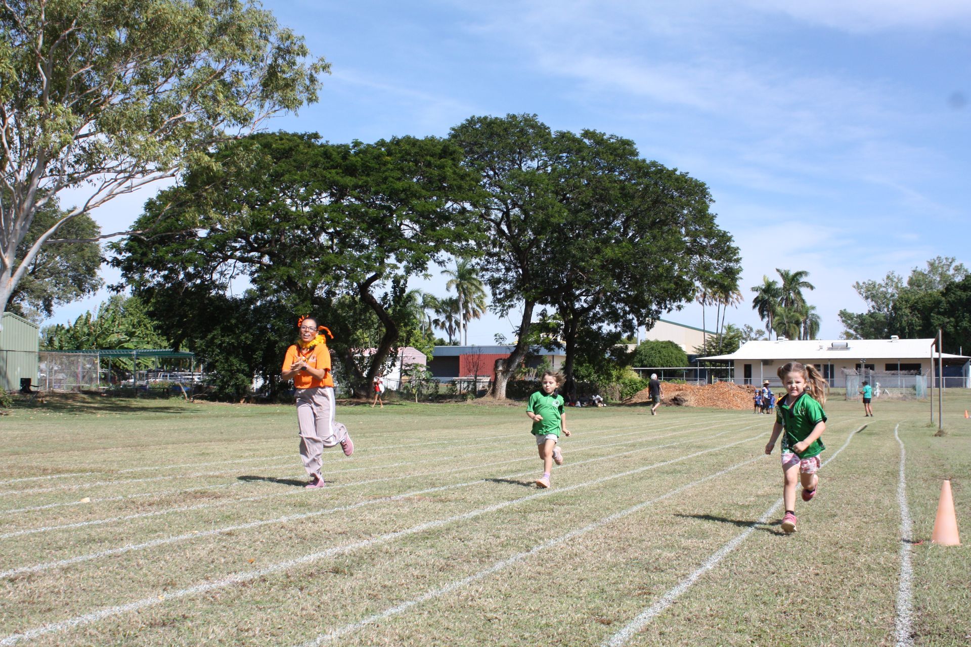 A group of children are running on a track in a field.
