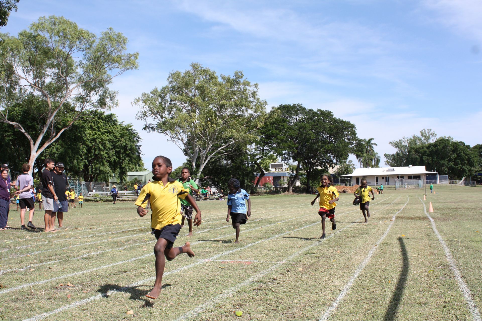 A group of children are running on a track in a field.