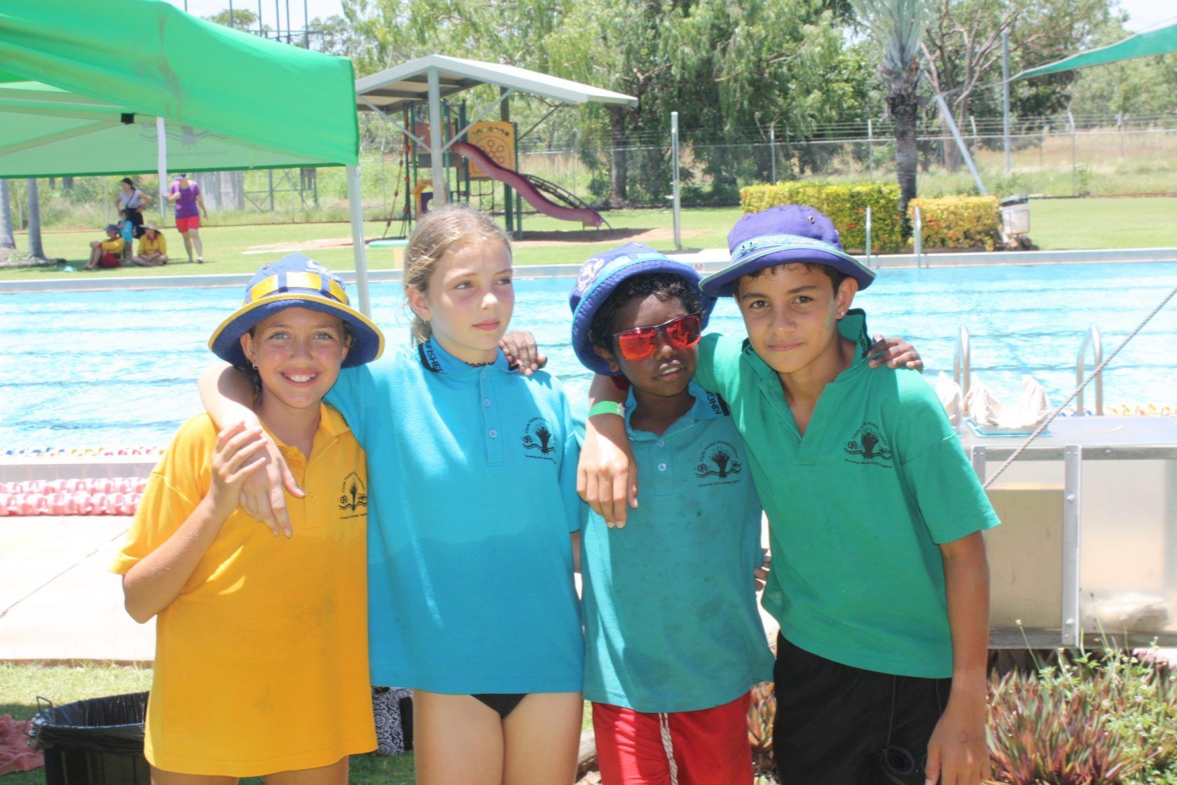 A group of children are posing for a picture in front of a swimming pool.