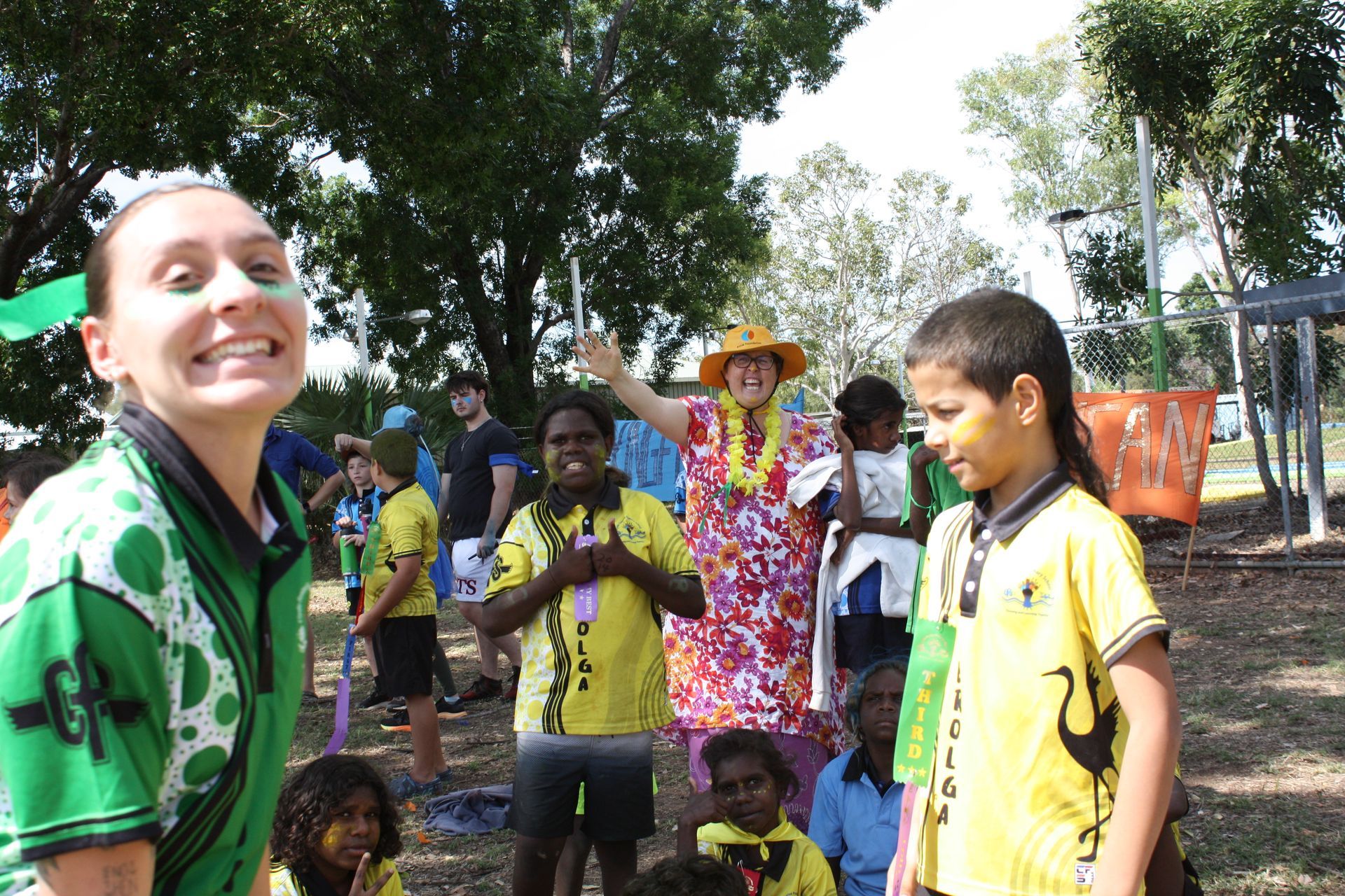 A woman in a green shirt stands in front of a group of children