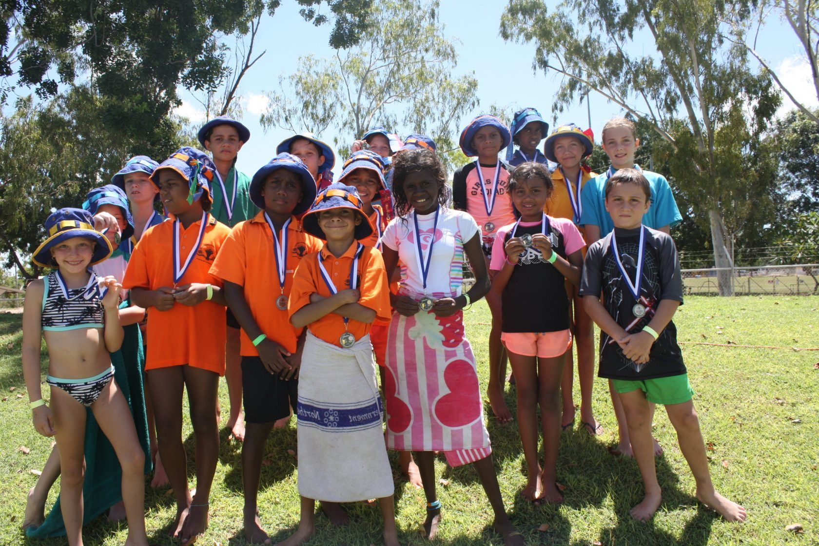 A group of children posing for a picture with medals around their necks