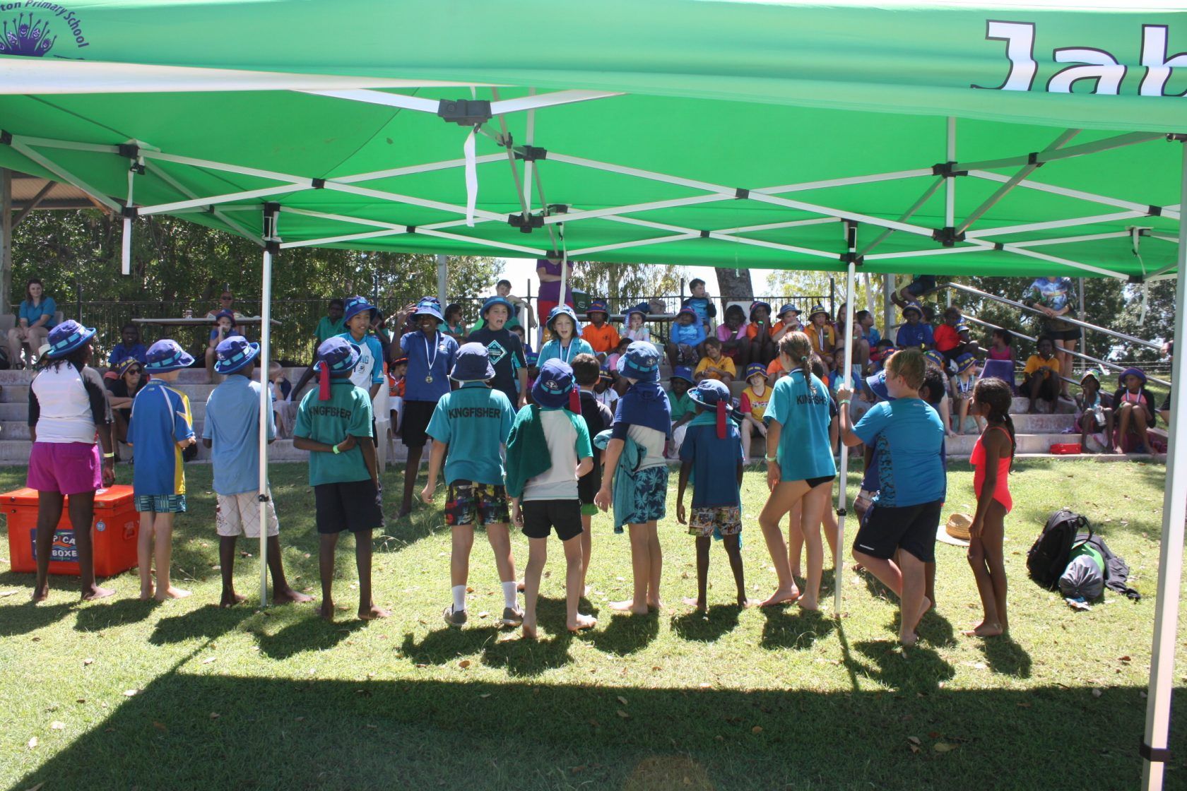 A group of children standing under a green tent that says lab