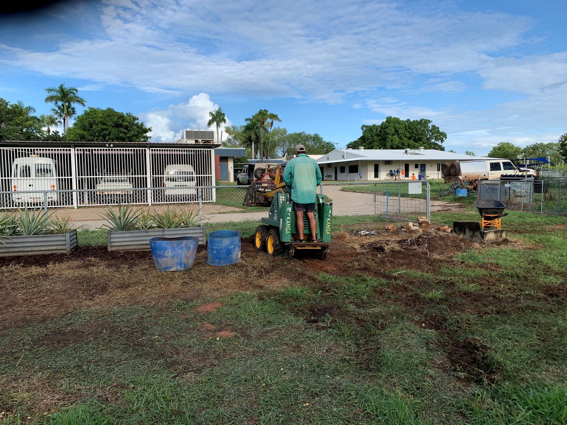 A man is riding a tractor in a field in front of a house.