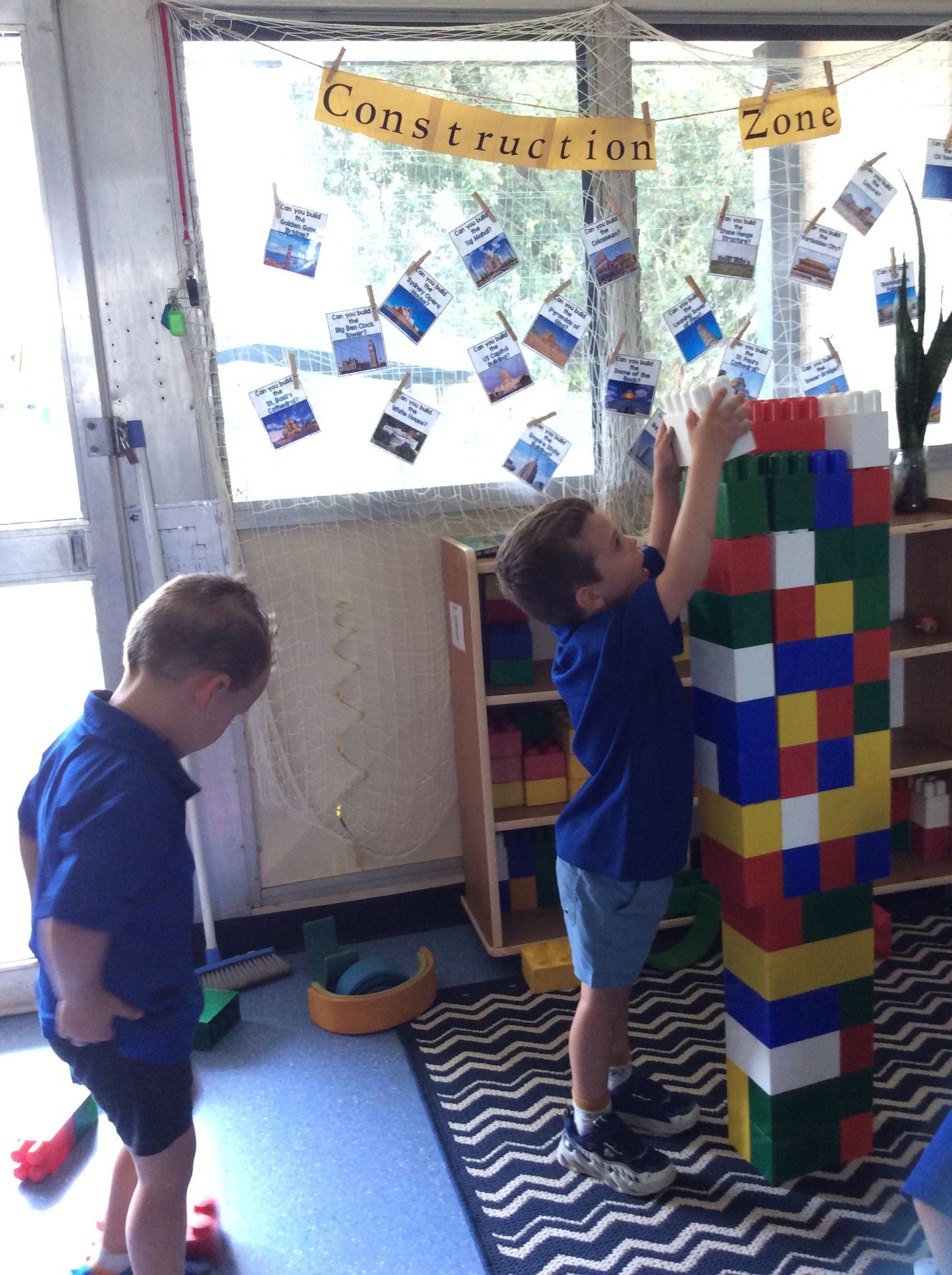 Two young boys are playing with lego blocks in a room with a sign that says construction zone