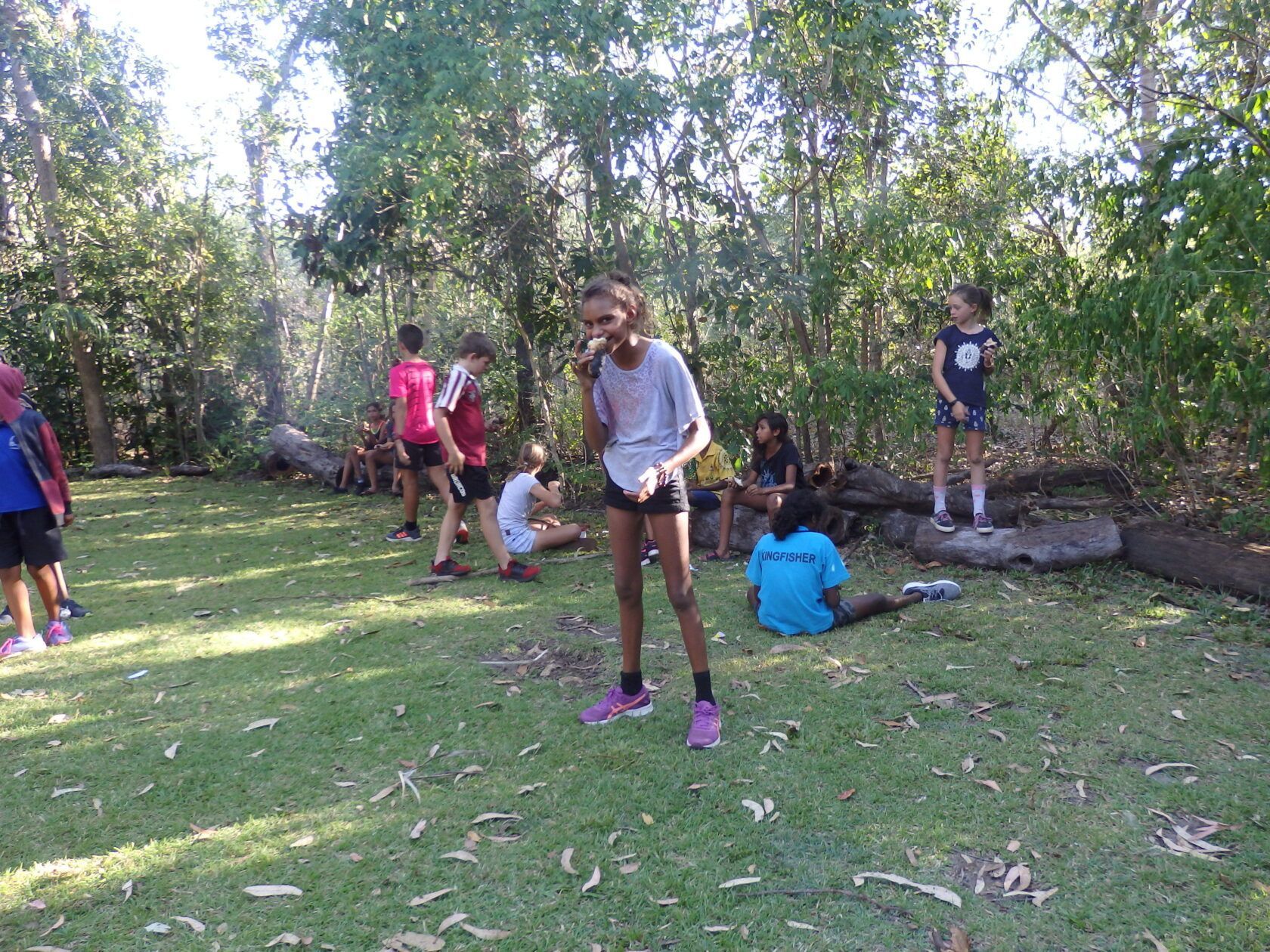 A group of children are playing in the grass in a park.