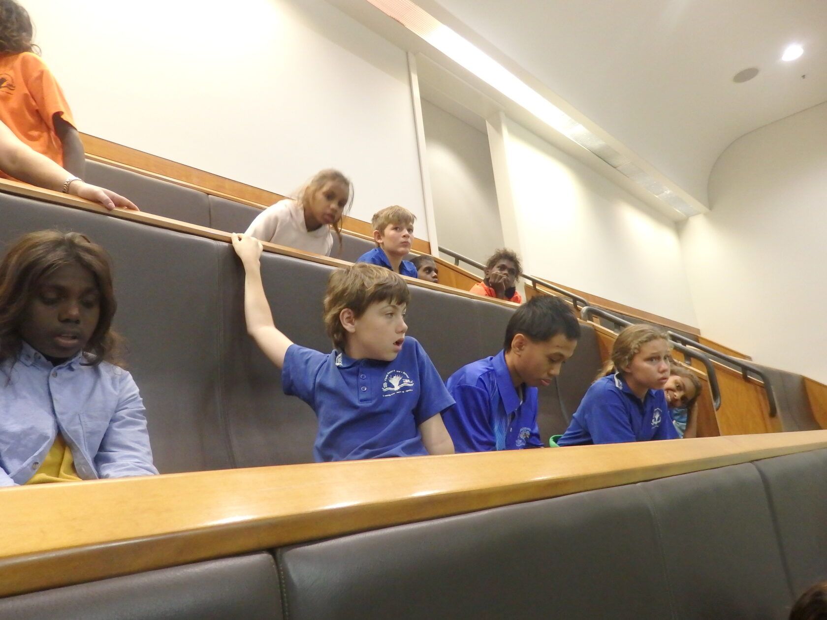 A group of children are sitting in a lecture hall