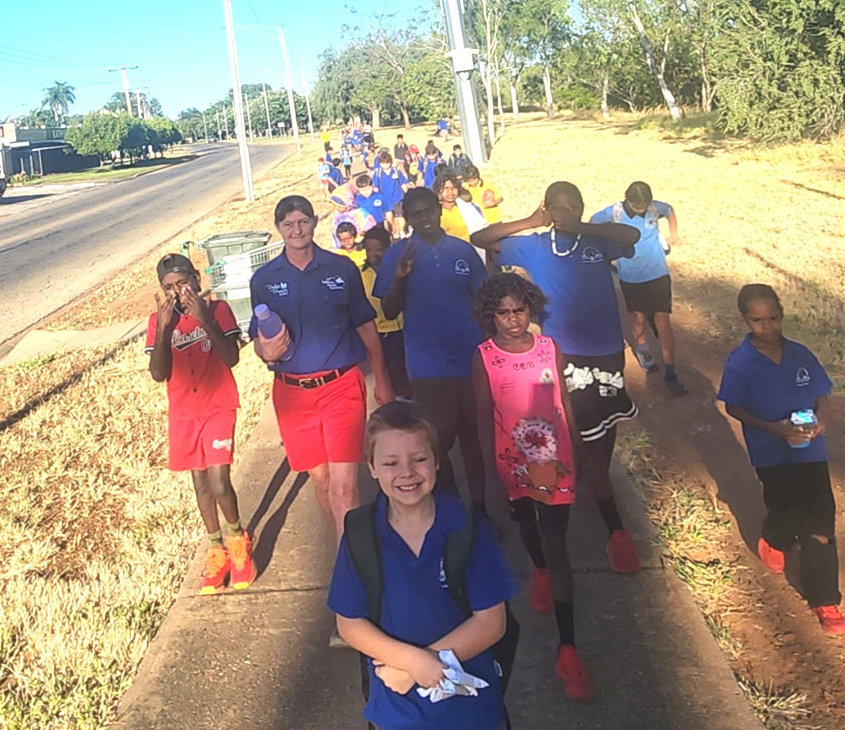A group of children are walking down a sidewalk