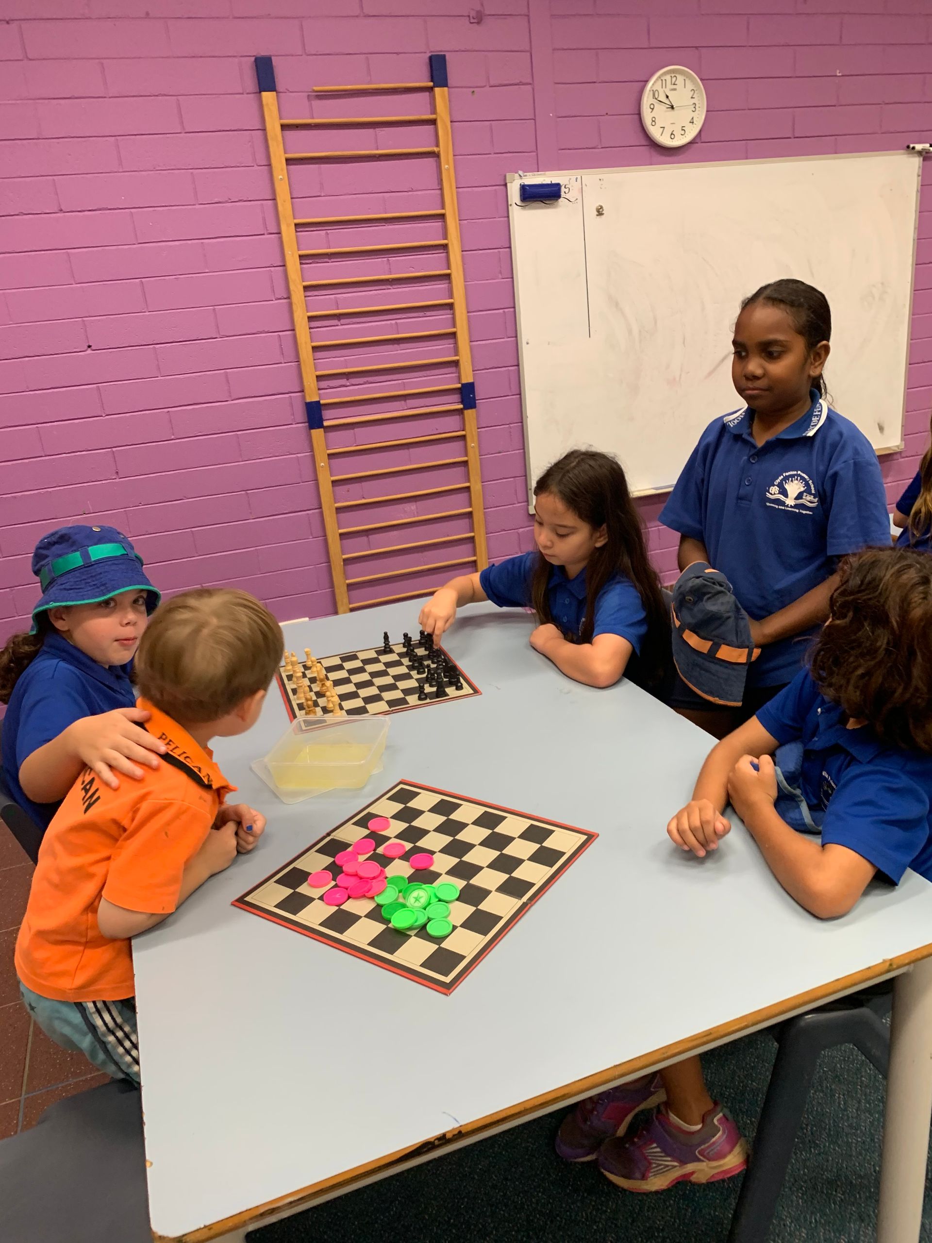 A group of children are sitting around a table playing chess