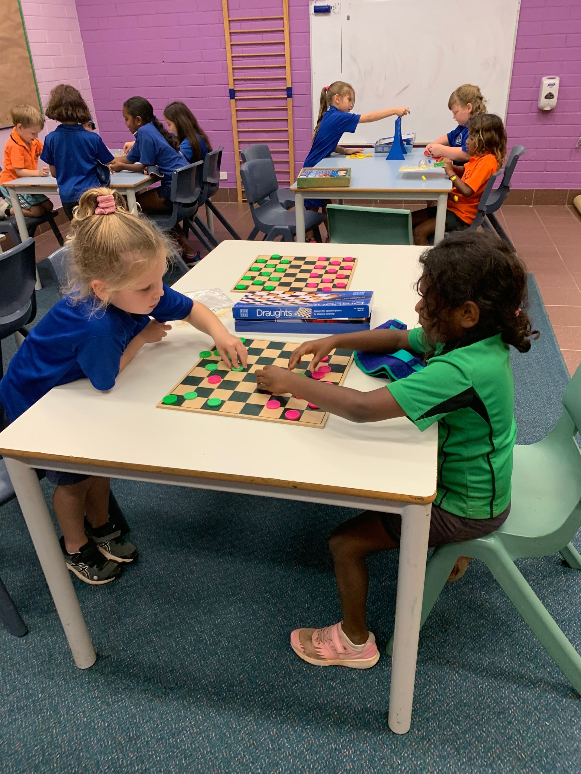 A group of children are playing a game of checkers at a table.