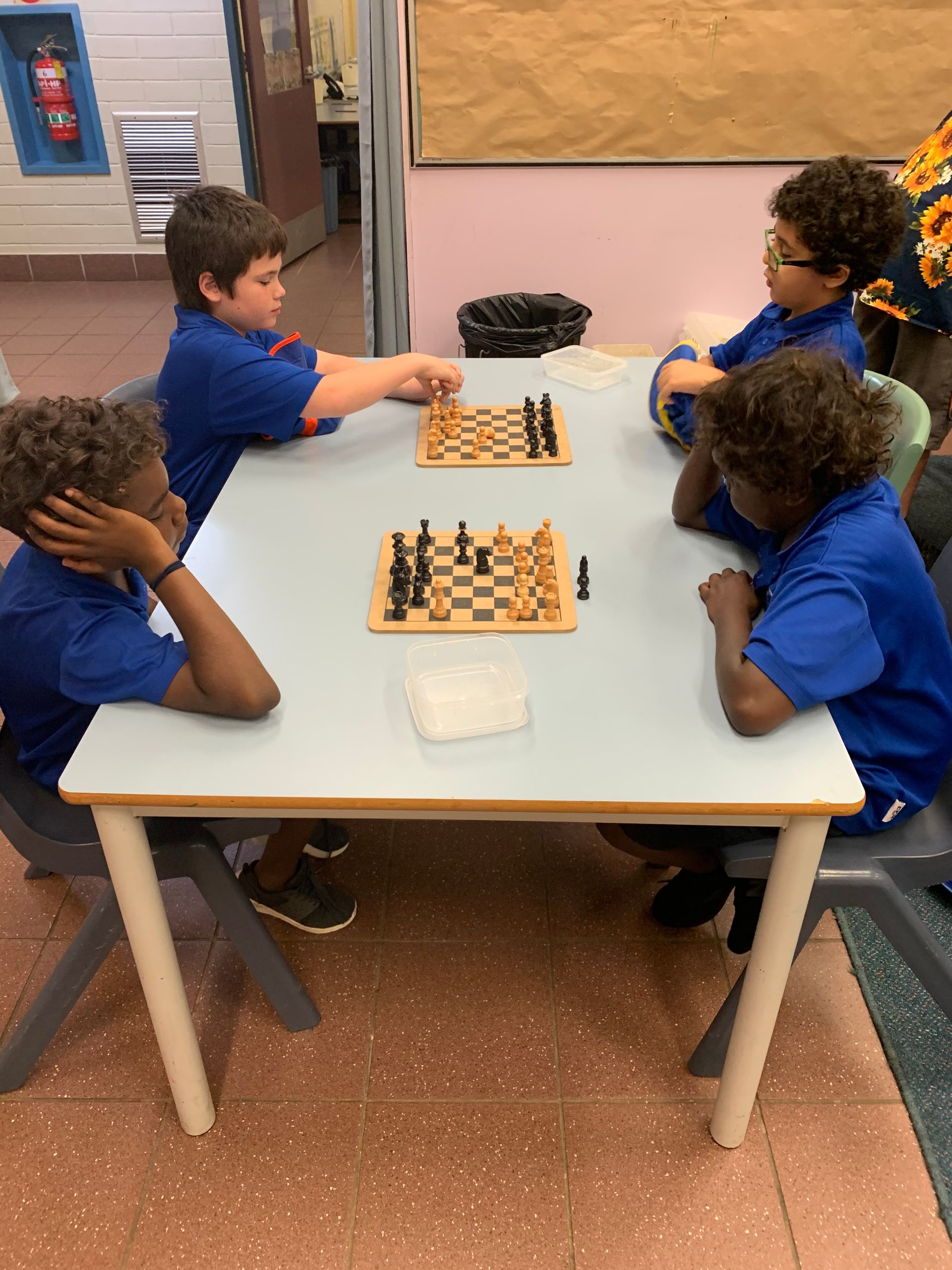A group of children are playing chess at a table